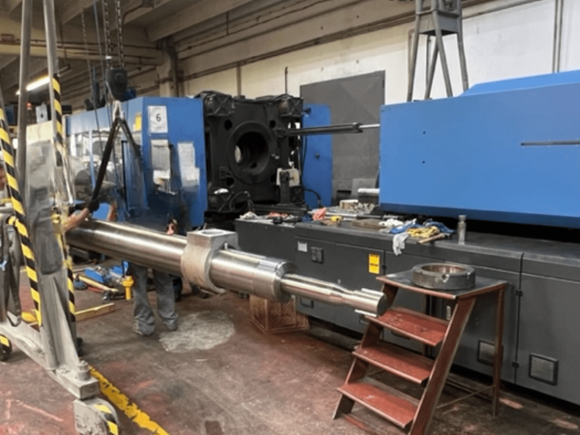 Hydraulische Spritzgießmaschine HAITIAN SA8000, dargestellt in einer Seitenansicht, während eine große Hydraulikstange angehoben wird.