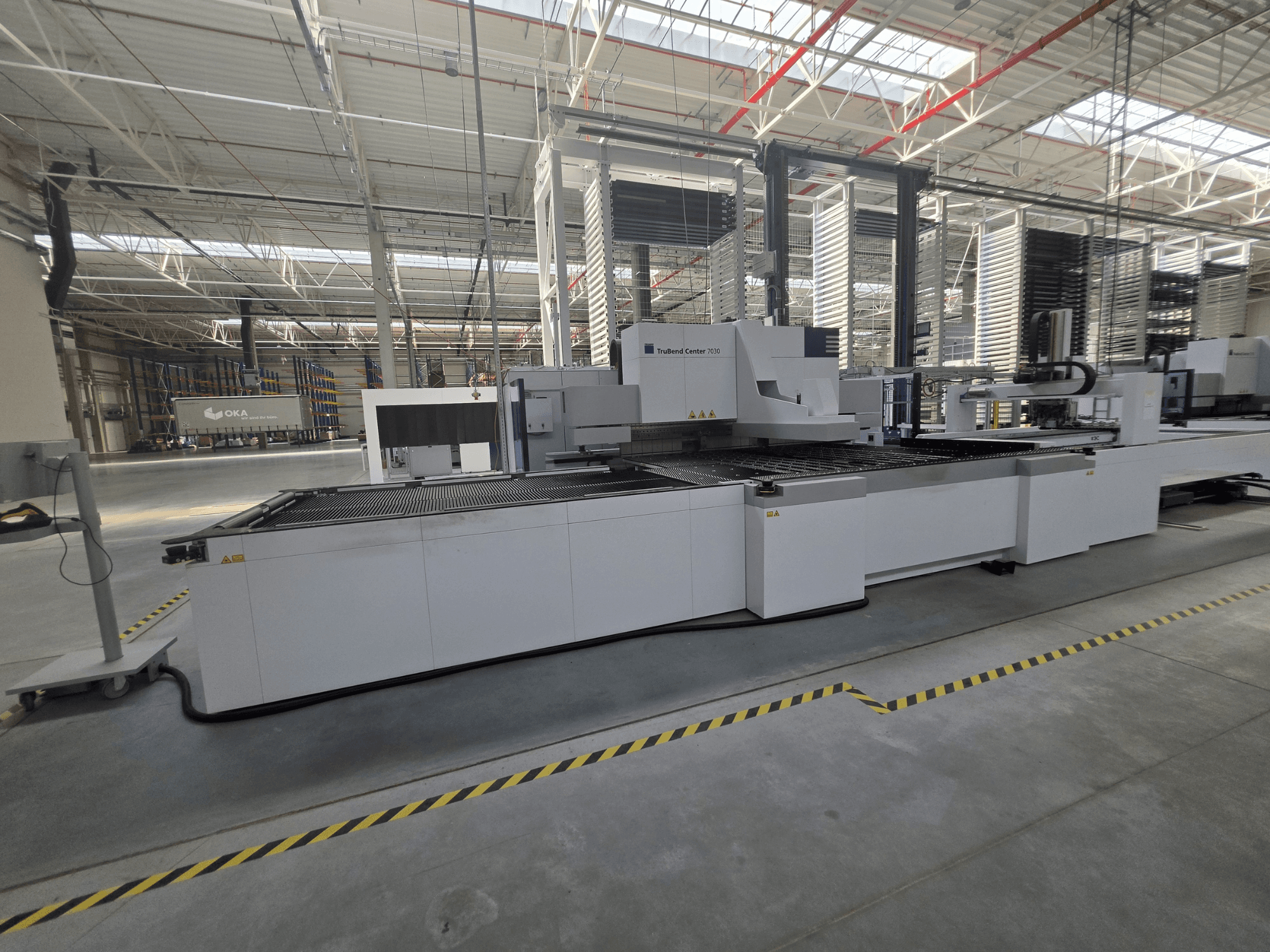 TRUMPF TruBend Center 7030 Abkantpresse, Seitenansicht, die den Arbeitsbereich und die Bedienelemente in einer großzügigen Werkstatt zeigt.