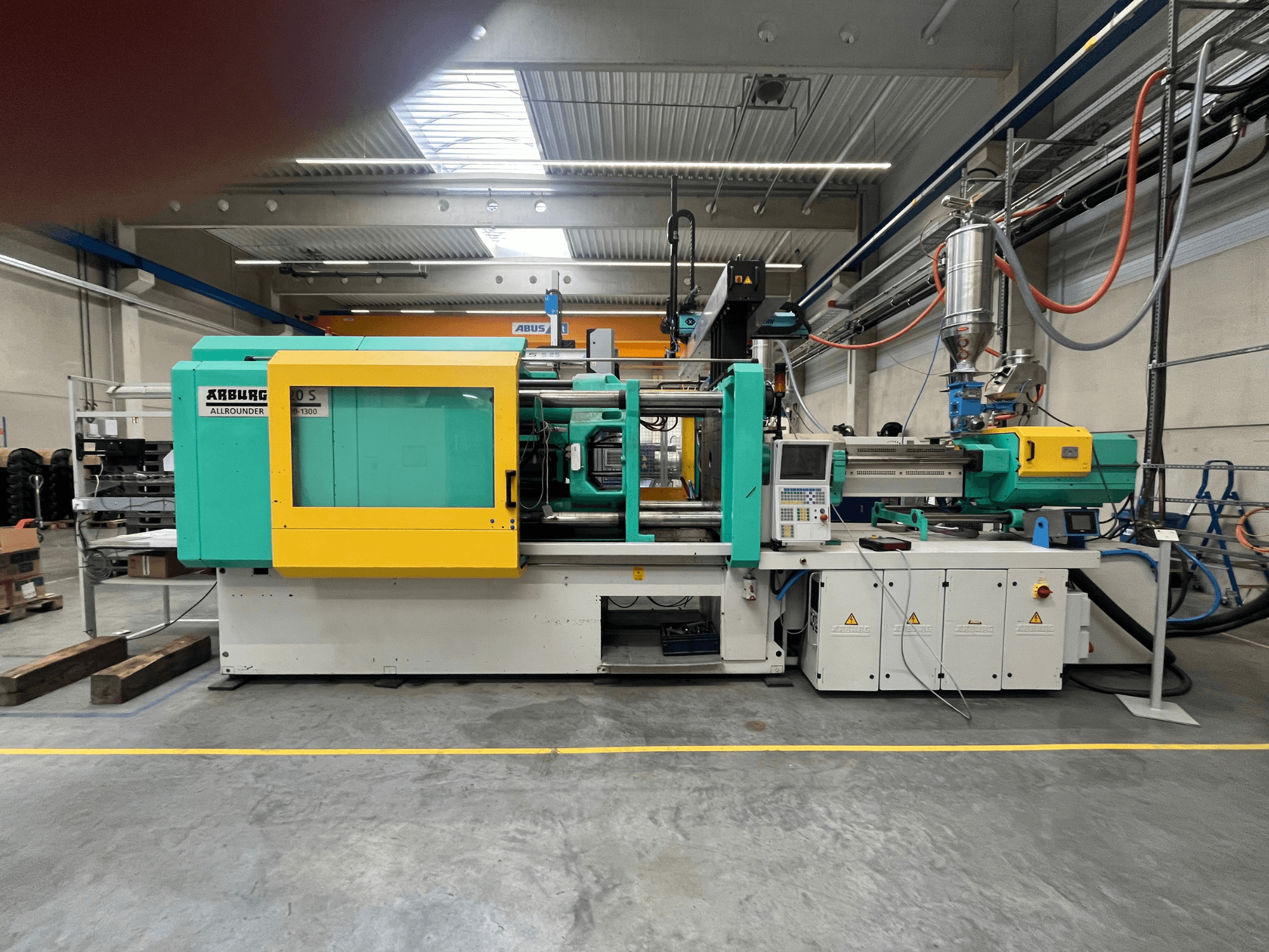 ARBURG Allrounder 370S Kunststoff-Spritzgießmaschine, Seitenansicht, mit grüner und gelber Verkleidung, Bedienoberfläche sichtbar.