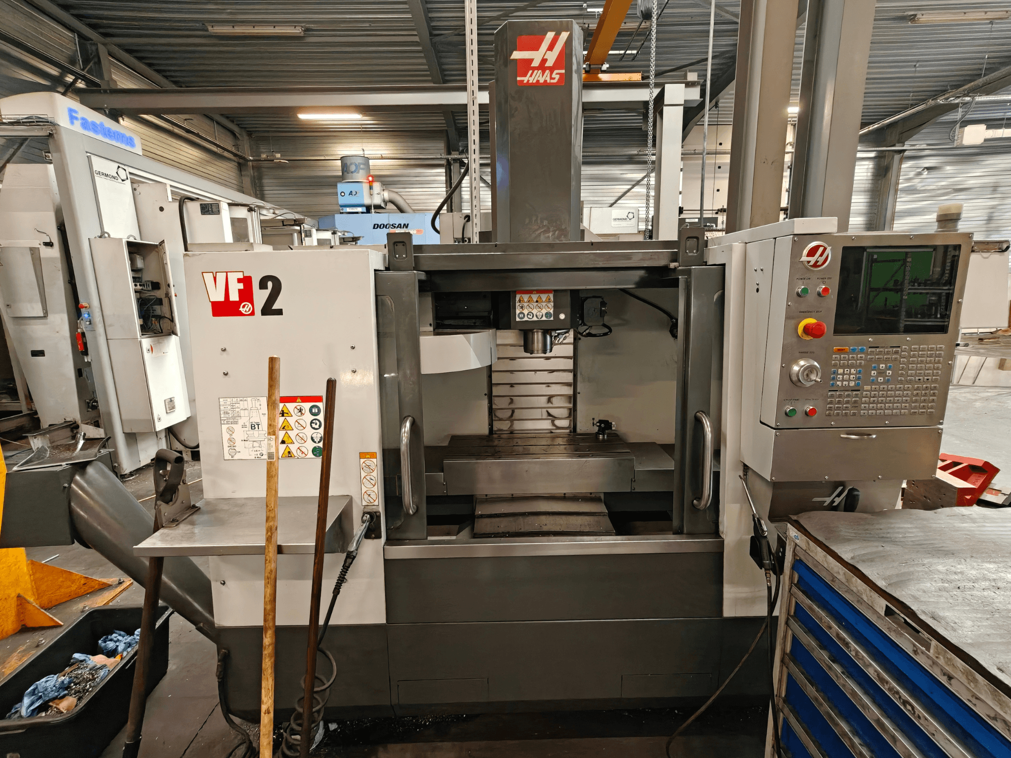 Vertikales Bearbeitungszentrum HAAS VF-2, Vorderansicht, mit Darstellung der Steuerung, der Spindel und des Arbeitstisches in einer Werkstattumgebung.