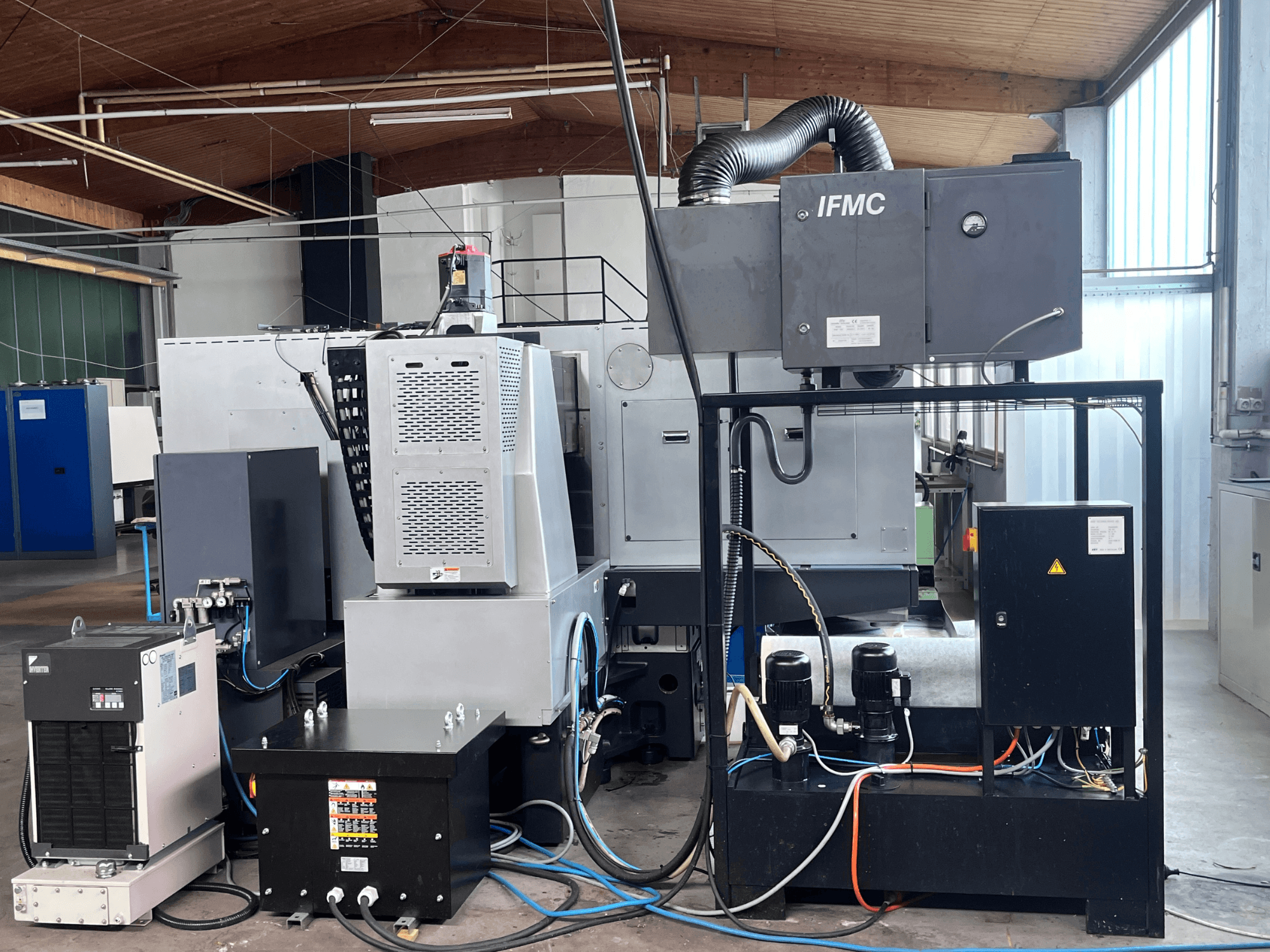 Flachschleifmaschine AMADA Techster 84, Ansicht von vorne mit Kühleinheit, Motoren und integriertem Bedienfeld.