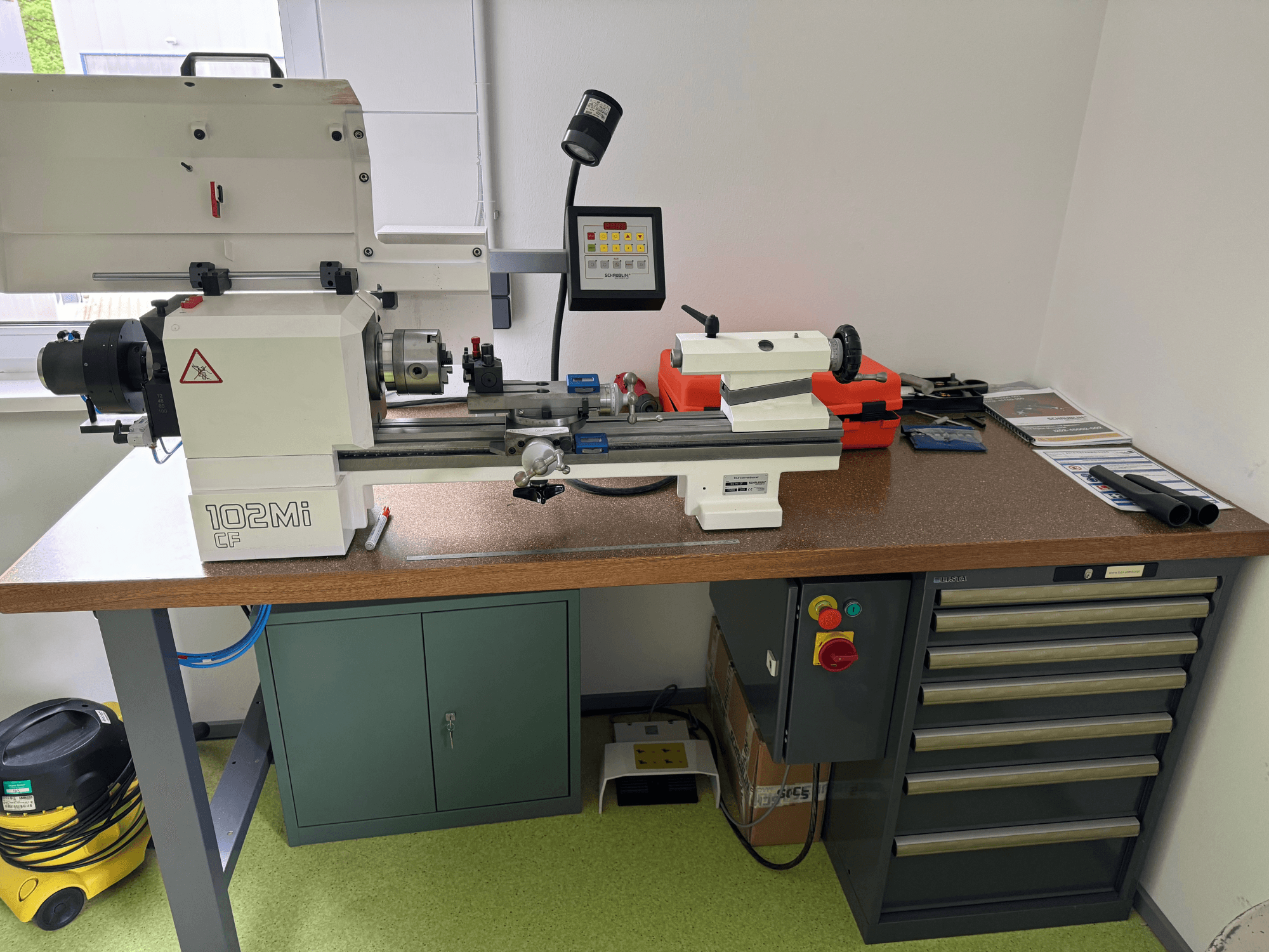 Horizontaldrehmaschine SCHAUBLIN 102Mi W25 in einer Werkstatt, Vorderansicht mit Details zum Bedienpult und zur Werkbank.