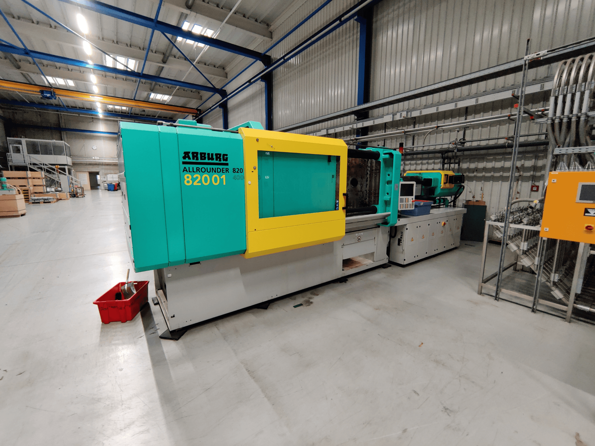Frontansicht einer hydraulischen Spritzgießmaschine Arburg 820 S 4000-2100 mit leuchtend grünen und gelben Platten.