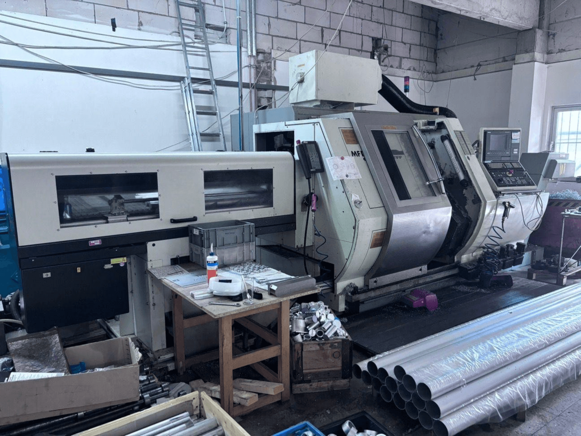Gildemeister MF Twin 65 Dreh-Fräszentrum, Seitenansicht mit Bedienfeld, Bearbeitungsbereich und Aluminiumrohren.