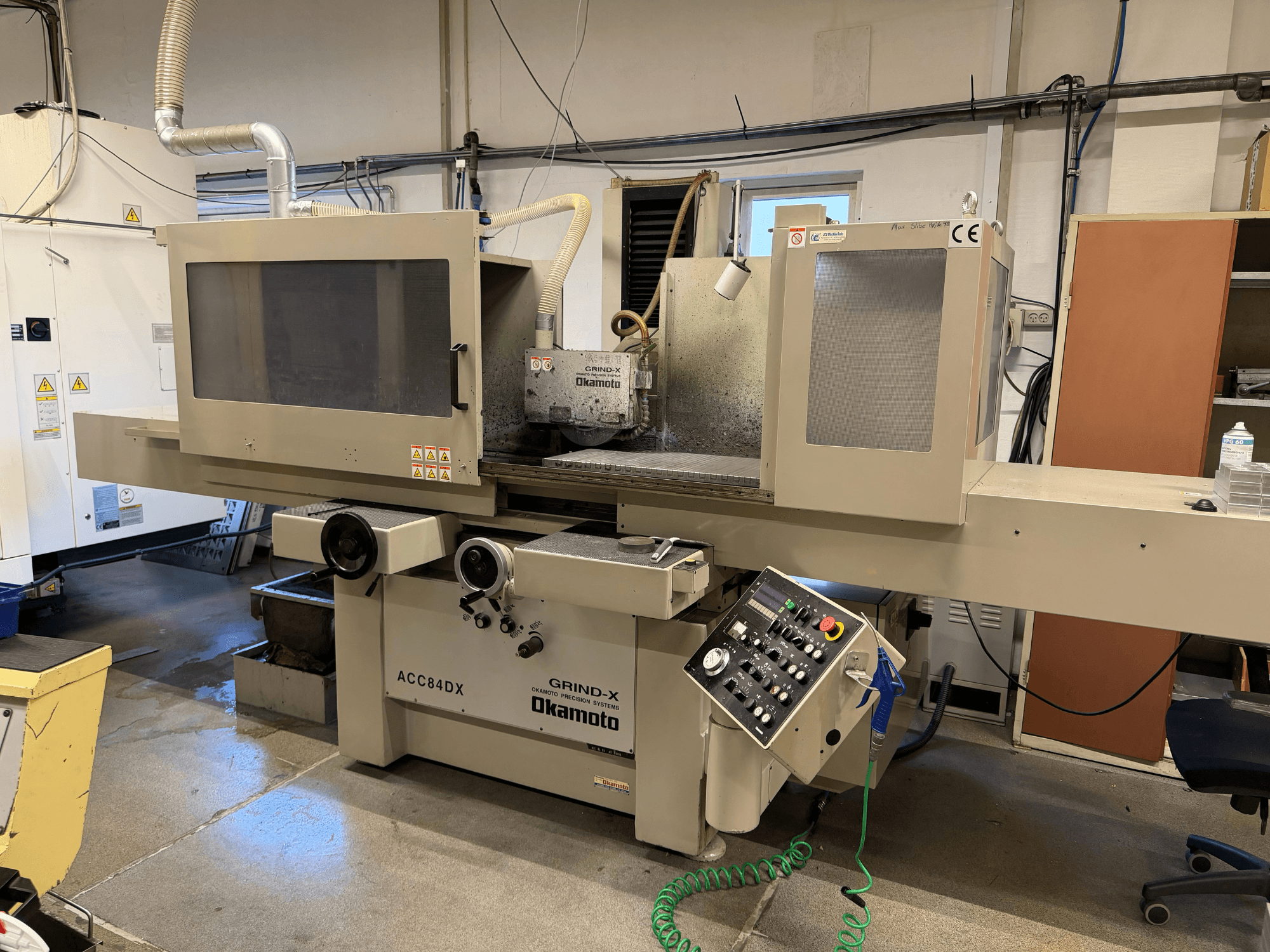 Vorderansicht der Flachschleifmaschine OKAMOTO ACC 84DX mit Bedienfeld und Kühlmittelsystem.