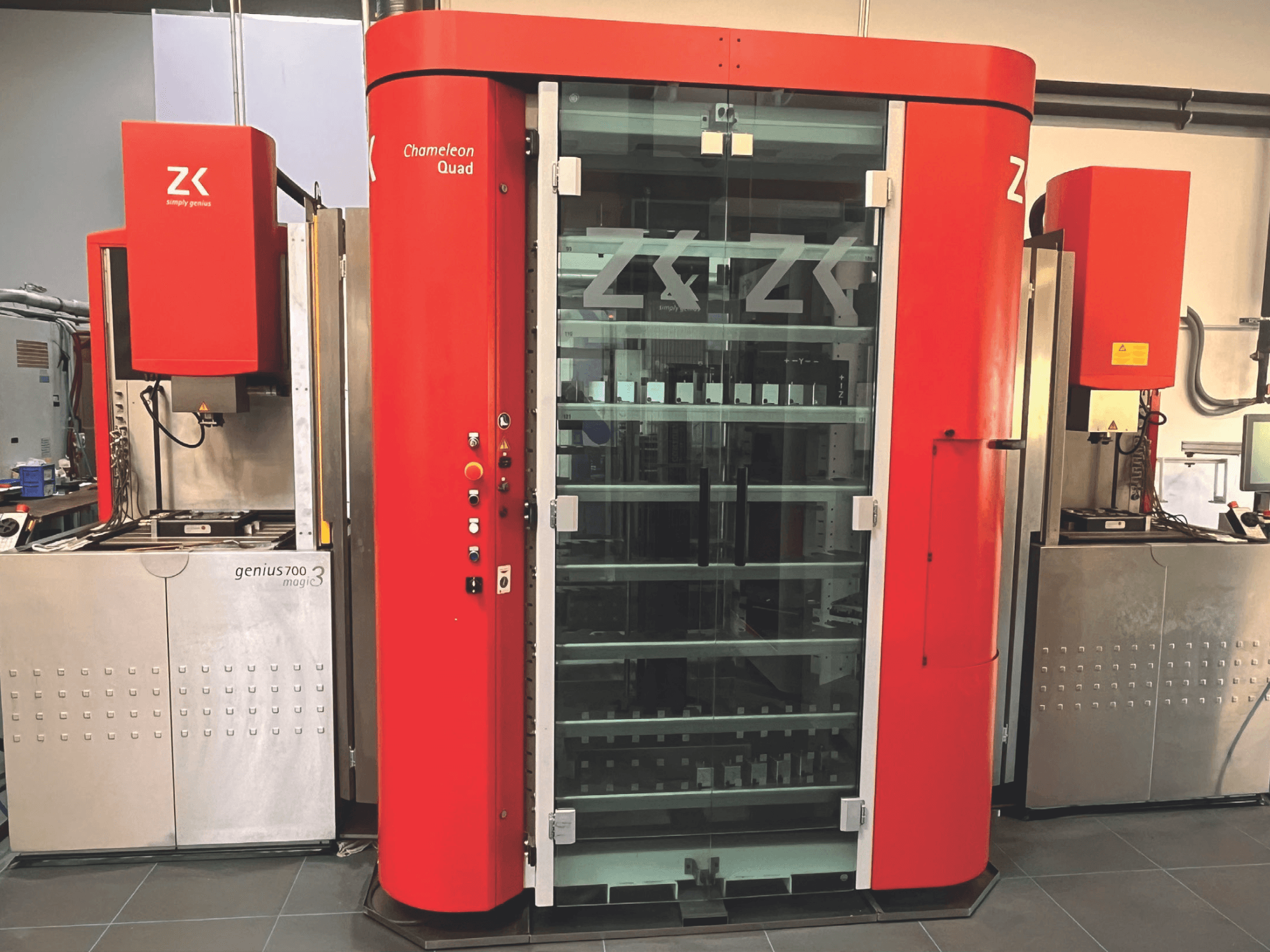 ZK Chameleon Quad, Vorderansicht, mit rotem Äußeren, Glasböden und danebenliegendem Genius 700 Magic 3 Gerät mit Bedienfeld.