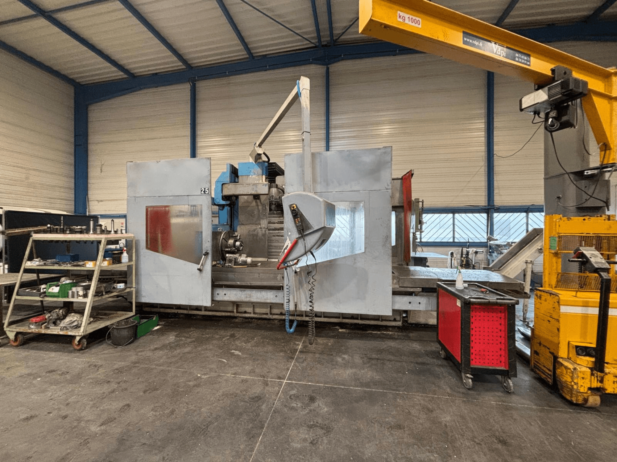 CNC-Fräsmaschine aus der Seitenansicht in einer Werkstatt; sichtbare Werkzeuge und Ablagefächer. Marke und Modell nicht angegeben.