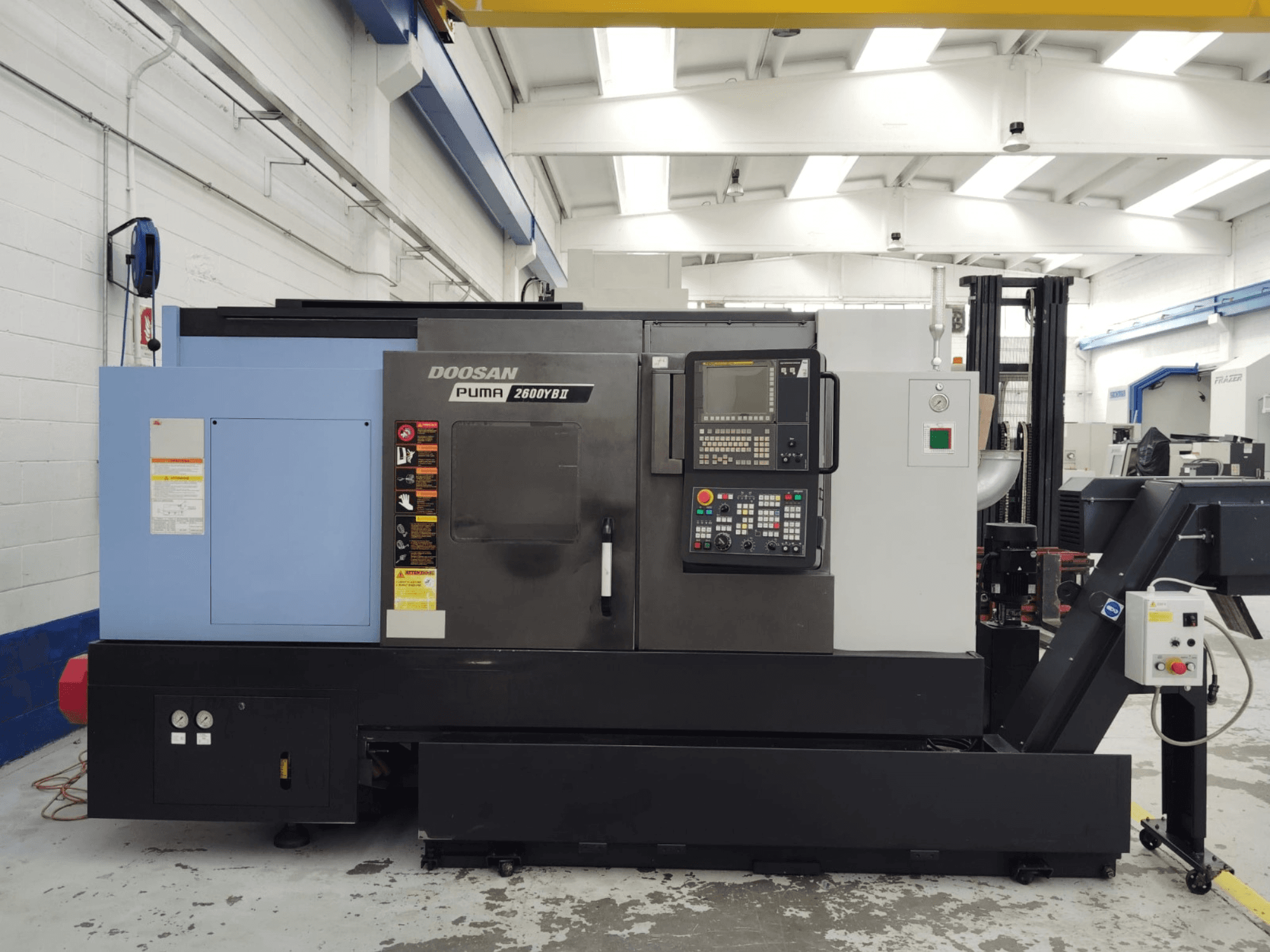 Vorderansicht der Horizontaldrehmaschine DOOSAN Puma 2600YB II mit sichtbarem Bedienfeld und Sicherheitsaufklebern.