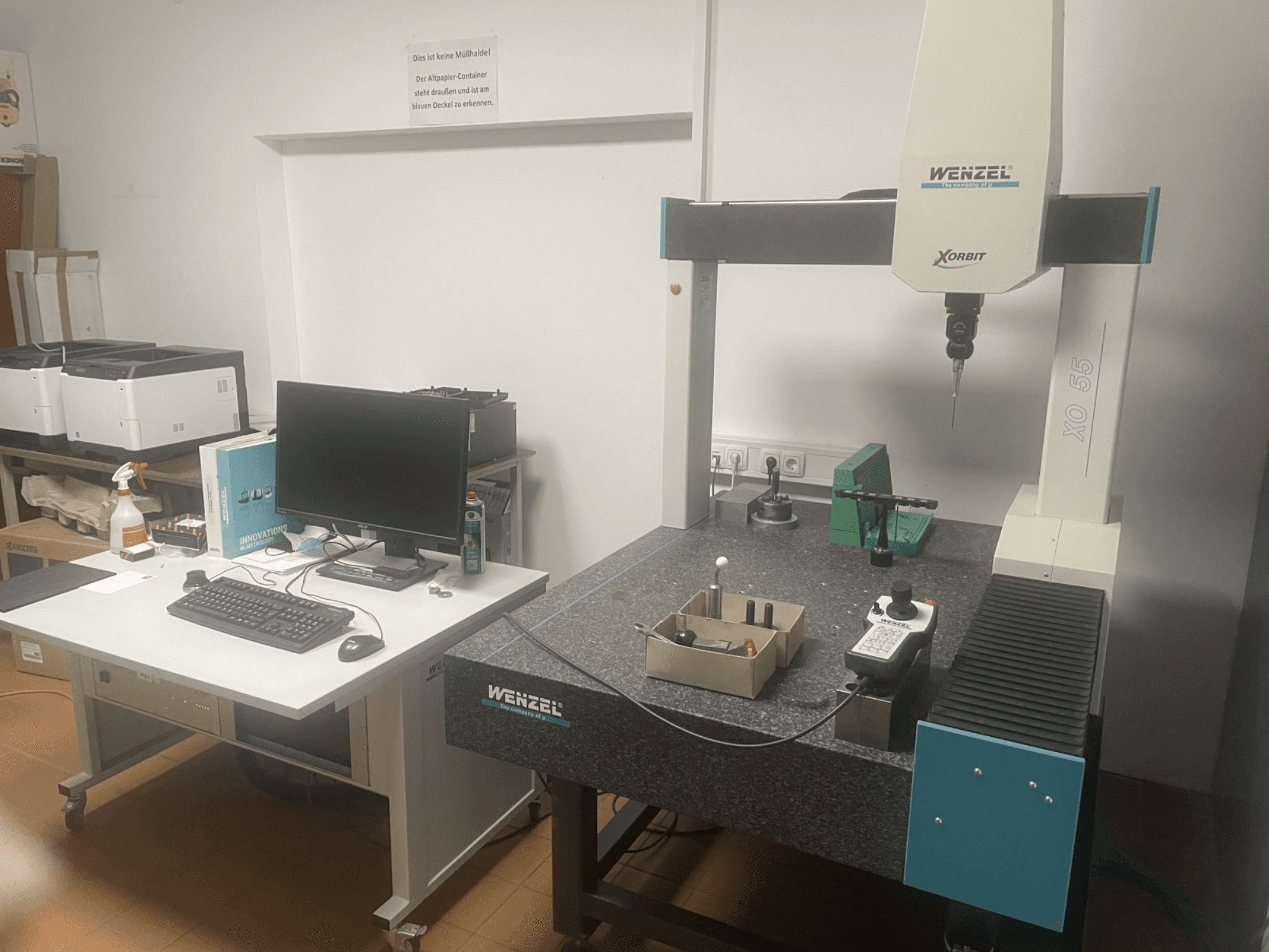 Wenzel XO 55 Koordinatenmessmaschine mit grünen Werkzeugen auf einem Granittisch, von vorne gesehen mit einer Computerstation.