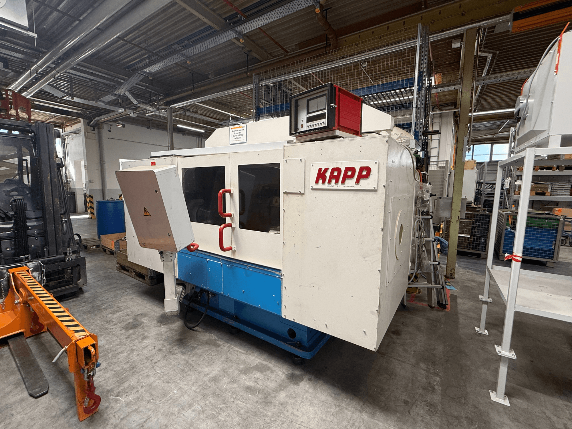 Die Zylinderschleifmaschine KAPP RNS 55 in Seitenansicht, mit Bedienfeld und Schutzabdeckung in einer Werkstattumgebung.