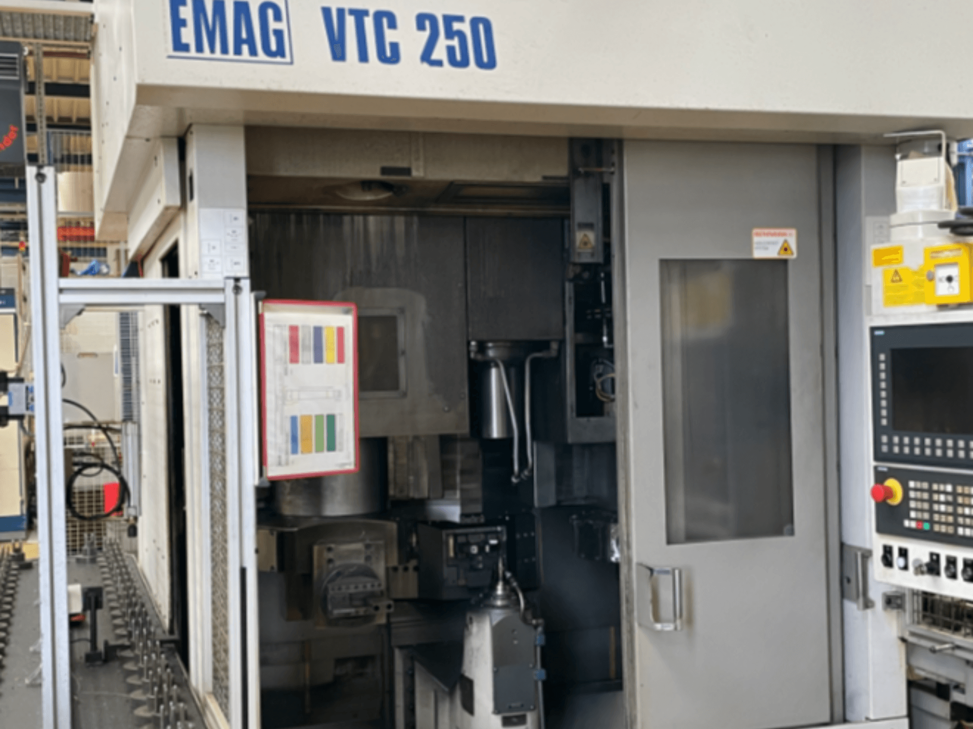 Vorderansicht der Vertikaldrehmaschine EMAG VTC 250 mit Bedienfeld, Bedienoberfläche und geöffneter Zugangsklappe.