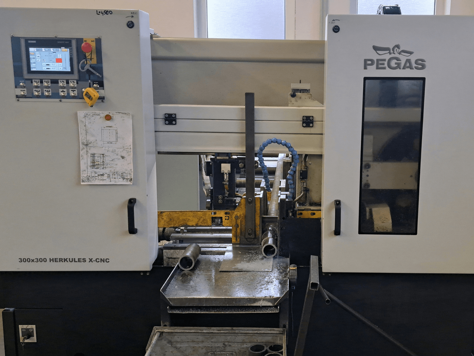 Pegas HERKULES X-CNC 300x300 Blechbearbeitungsmaschine, Vorderansicht, mit Bedienfeld und Arbeitsbereich mit Metallteilen.