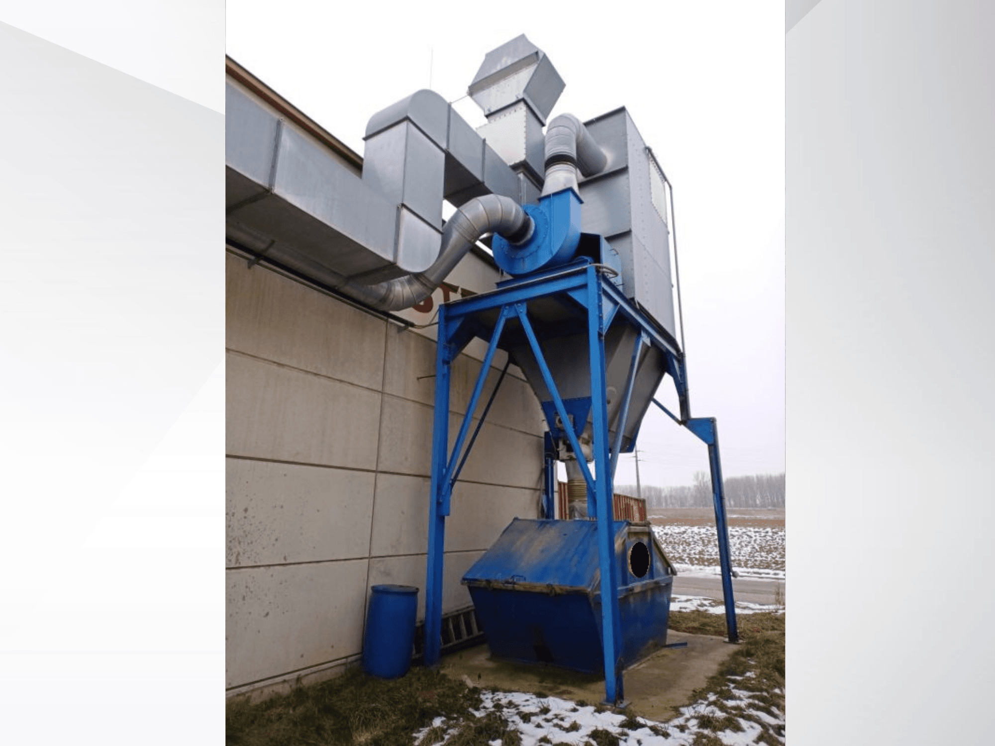 LBH-Sauganlage in Blau mit zylindrischem Abscheider und Anschlussleitungen, Frontansicht vor verschneitem Hintergrund.
