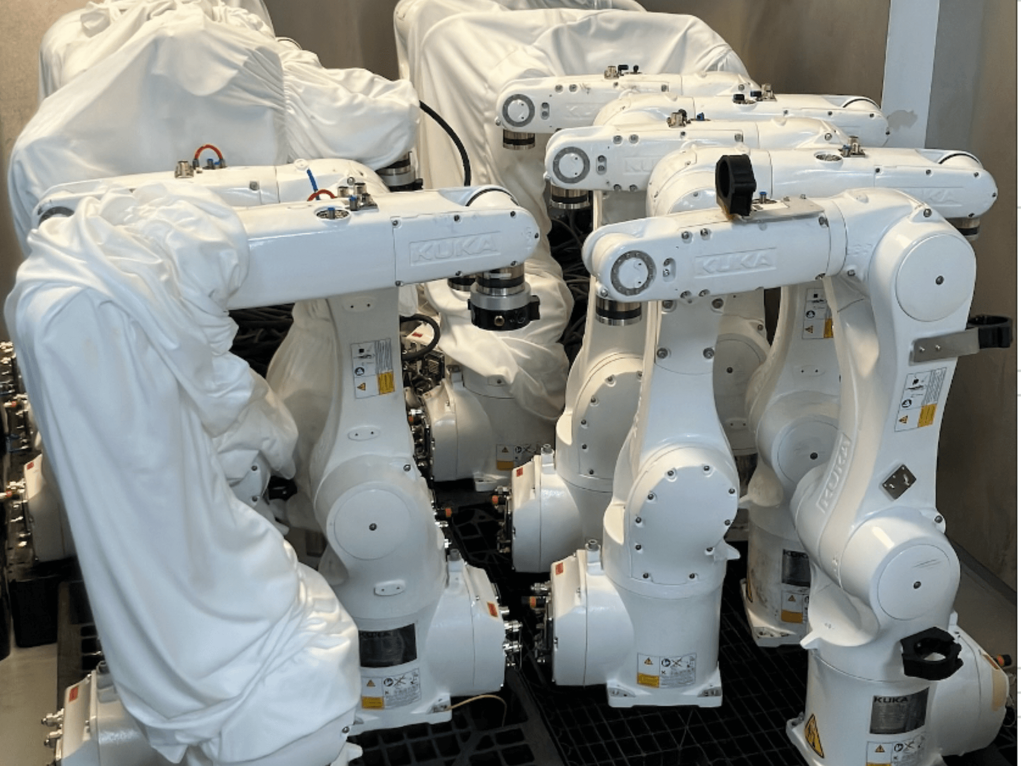 Mit weißem Stoff bespannte KUKA KR 10 R900-2-Roboterarme, von oben gesehen, mit mehreren Einheiten im Lager.