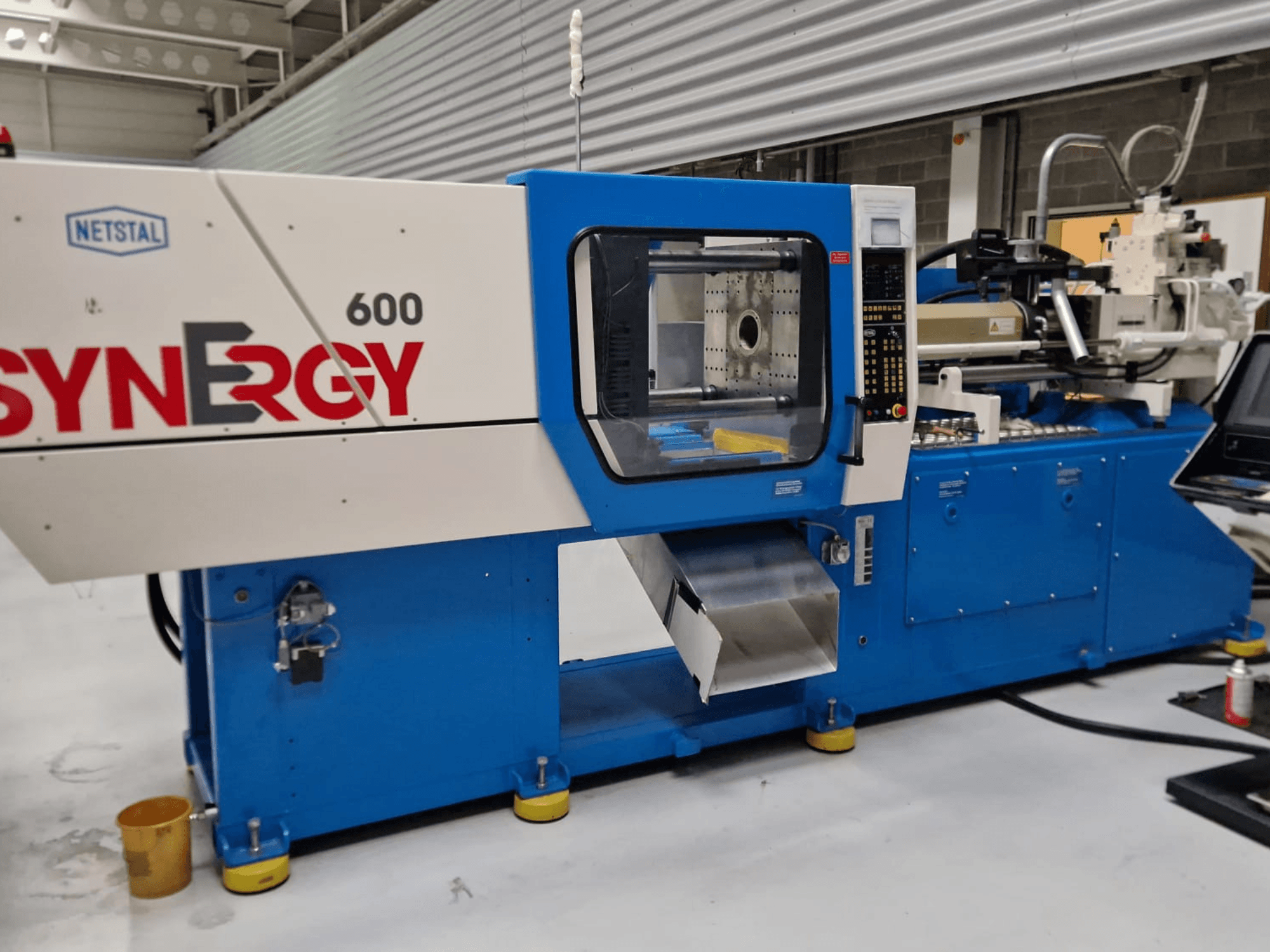 Hydraulische Spritzgießmaschine Netstal Synergy 600-230, Seitenansicht mit Bedienfeld und Einspritzbereich.