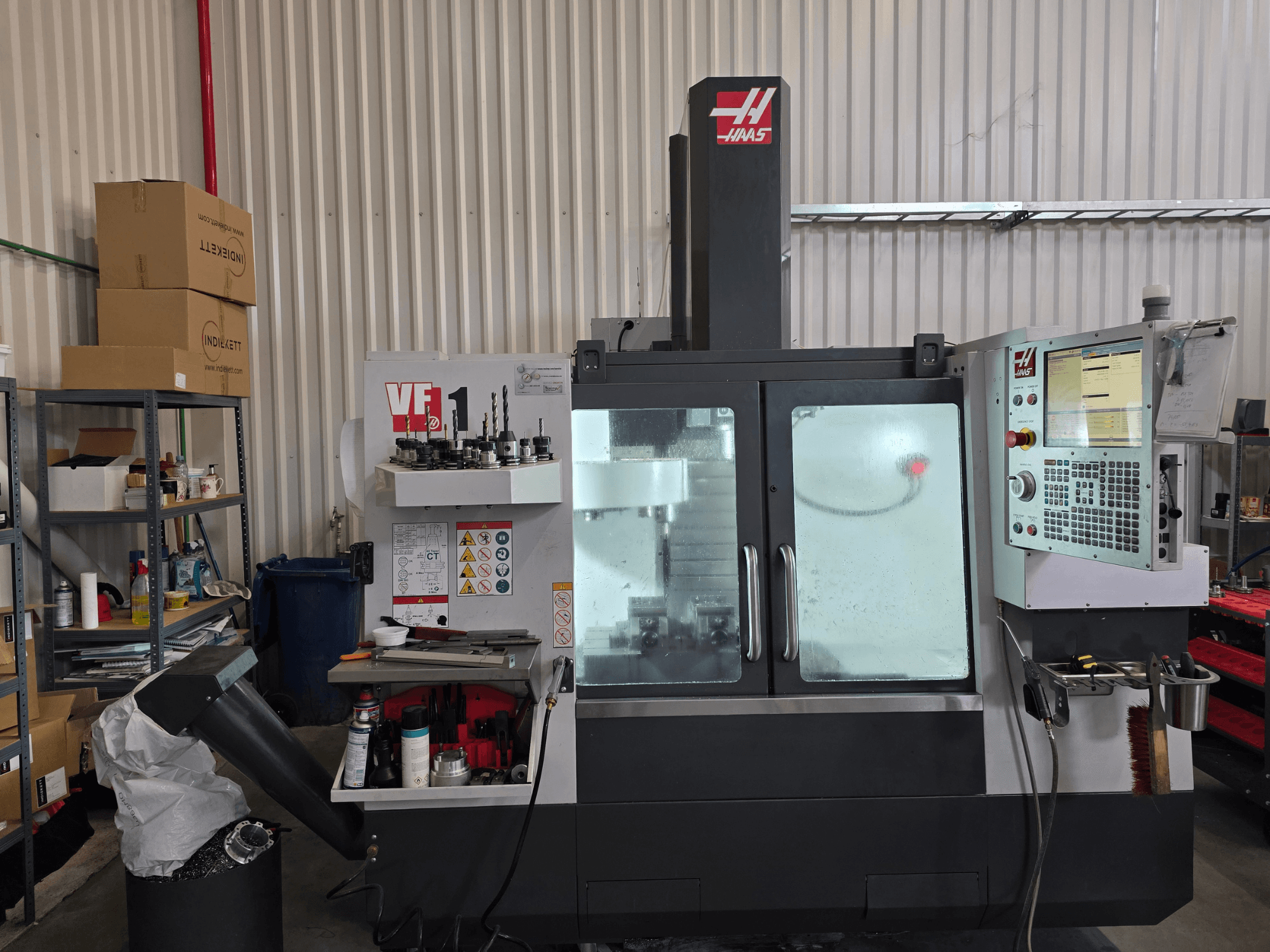 HAAS VF 1 Vertikal-Bearbeitungszentrum in einer Werkstatt, Frontansicht mit Bedienfeld und Fräsbereich mit Werkzeugen.