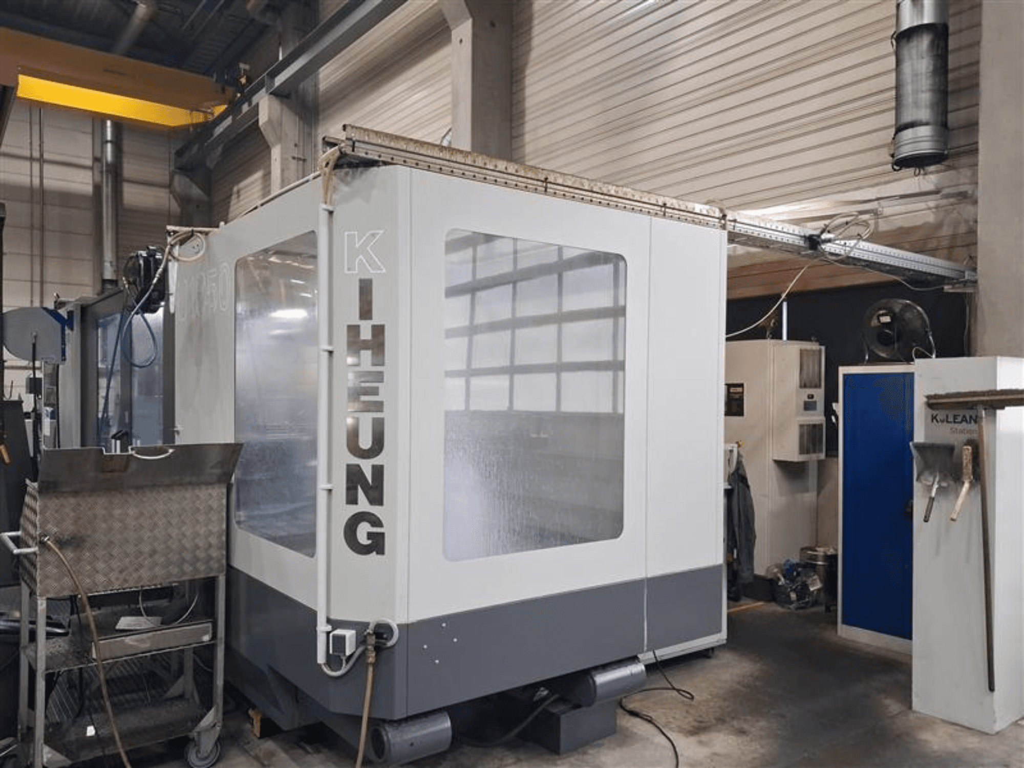 Bettfräsmaschine KIHEUNG Volmatec KNC U1050, Vorderansicht mit Metallgehäuse und Steuereinheit im Hintergrund.