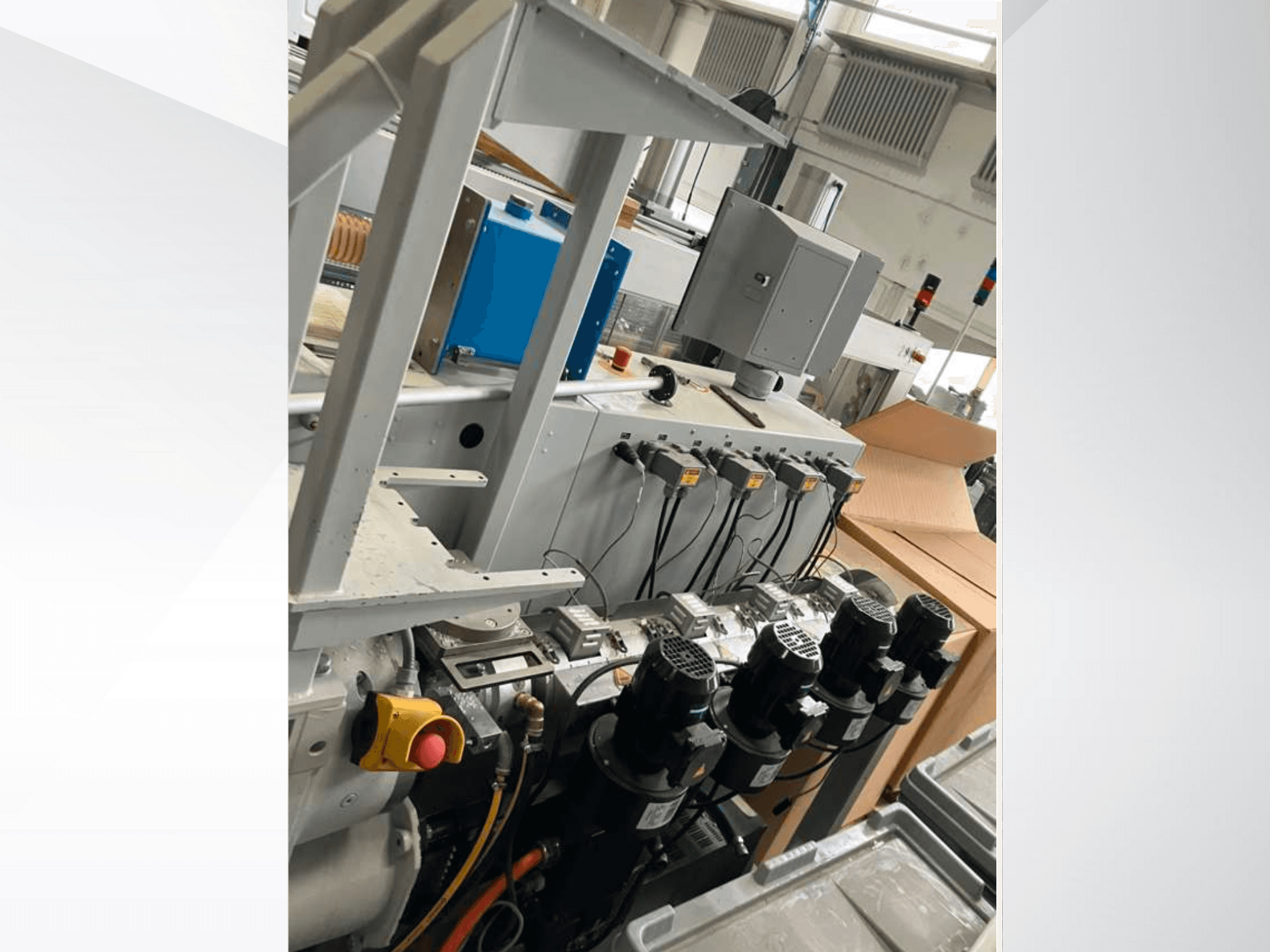 Schalttafel für Industriemaschinen mit mehreren Motoren, Messgeräten und einem Monitor; Seitenansicht in einer Fabrikumgebung.