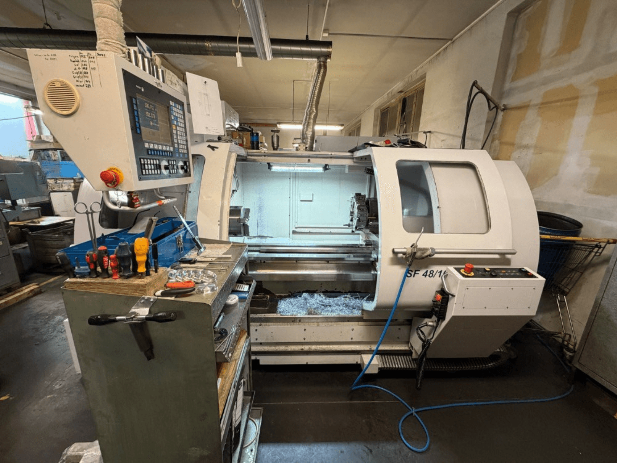 Horizontal-Drehmaschine MICROCUT SF 48/1000 von vorne gesehen, mit Bedienfeld und Werkzeugen auf dem Arbeitstisch.