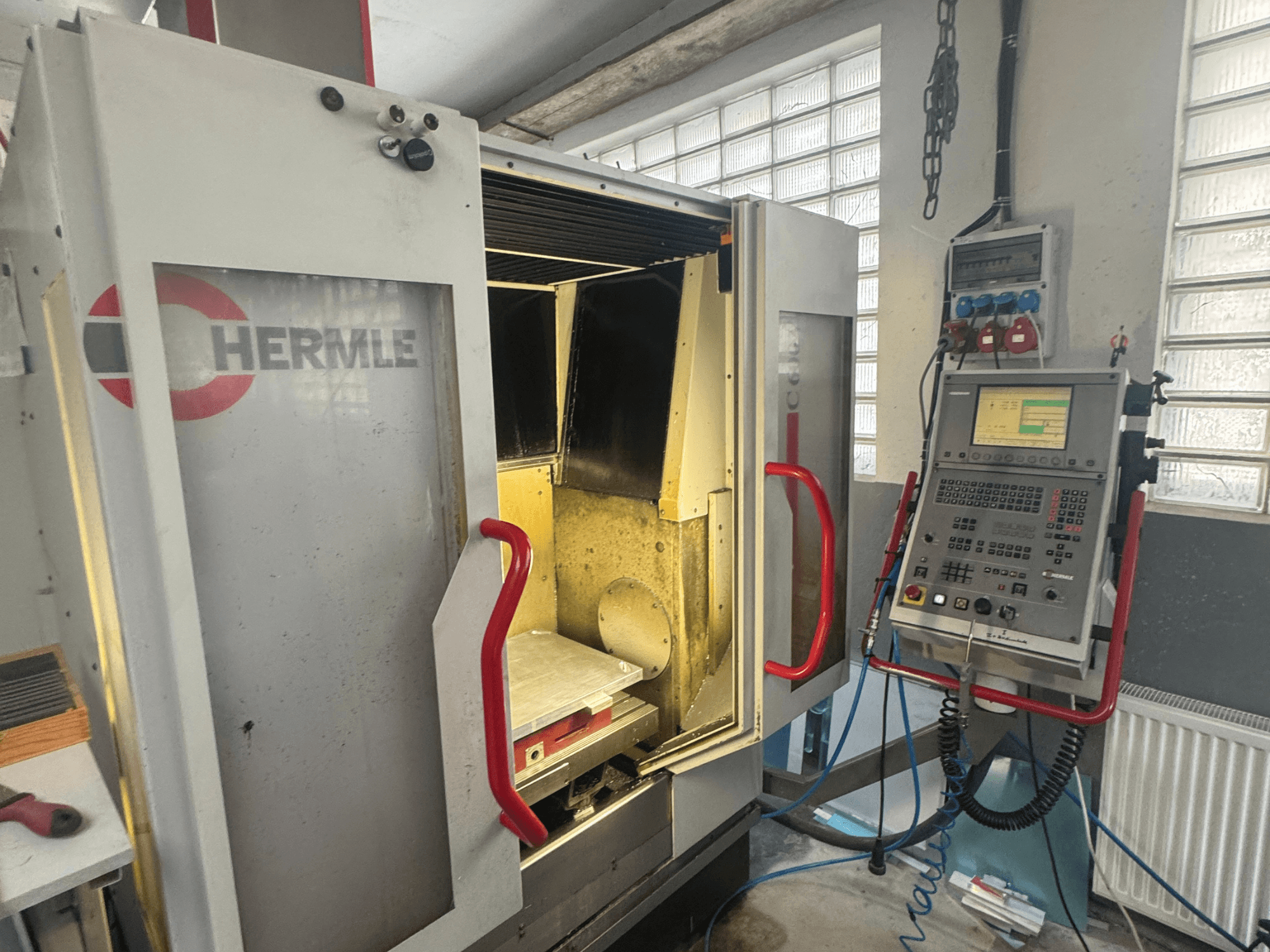 HERMLE C600V Vertikal-Bearbeitungszentrum, Vorderansicht mit geöffneter Tür, Bedienfeld und innerem Arbeitsbereich.