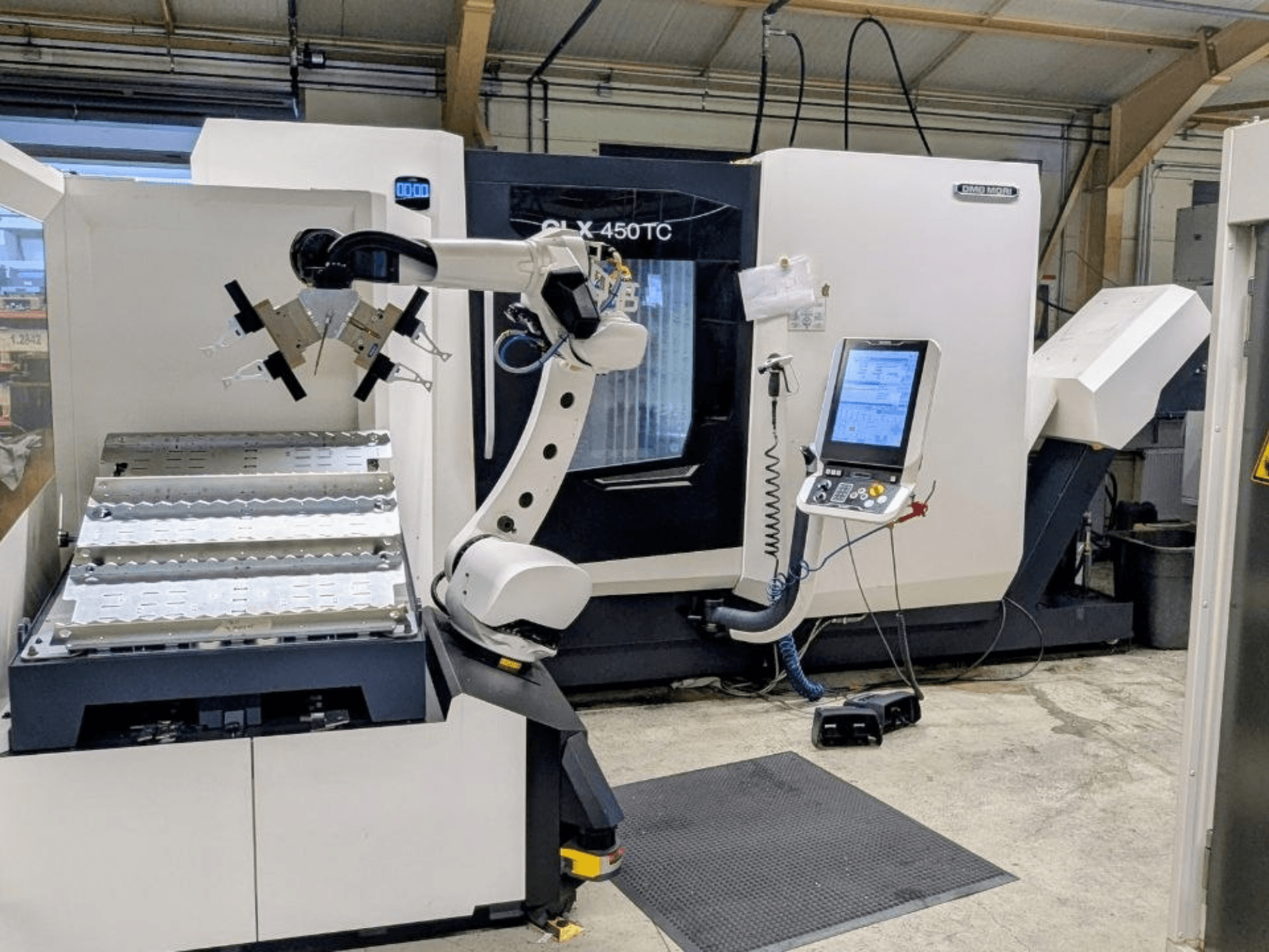 DMG MORI CLX 450 TC mit Robo2go, Vorderansicht, mit Roboterarm und Bedienfeld neben der Maschine.
