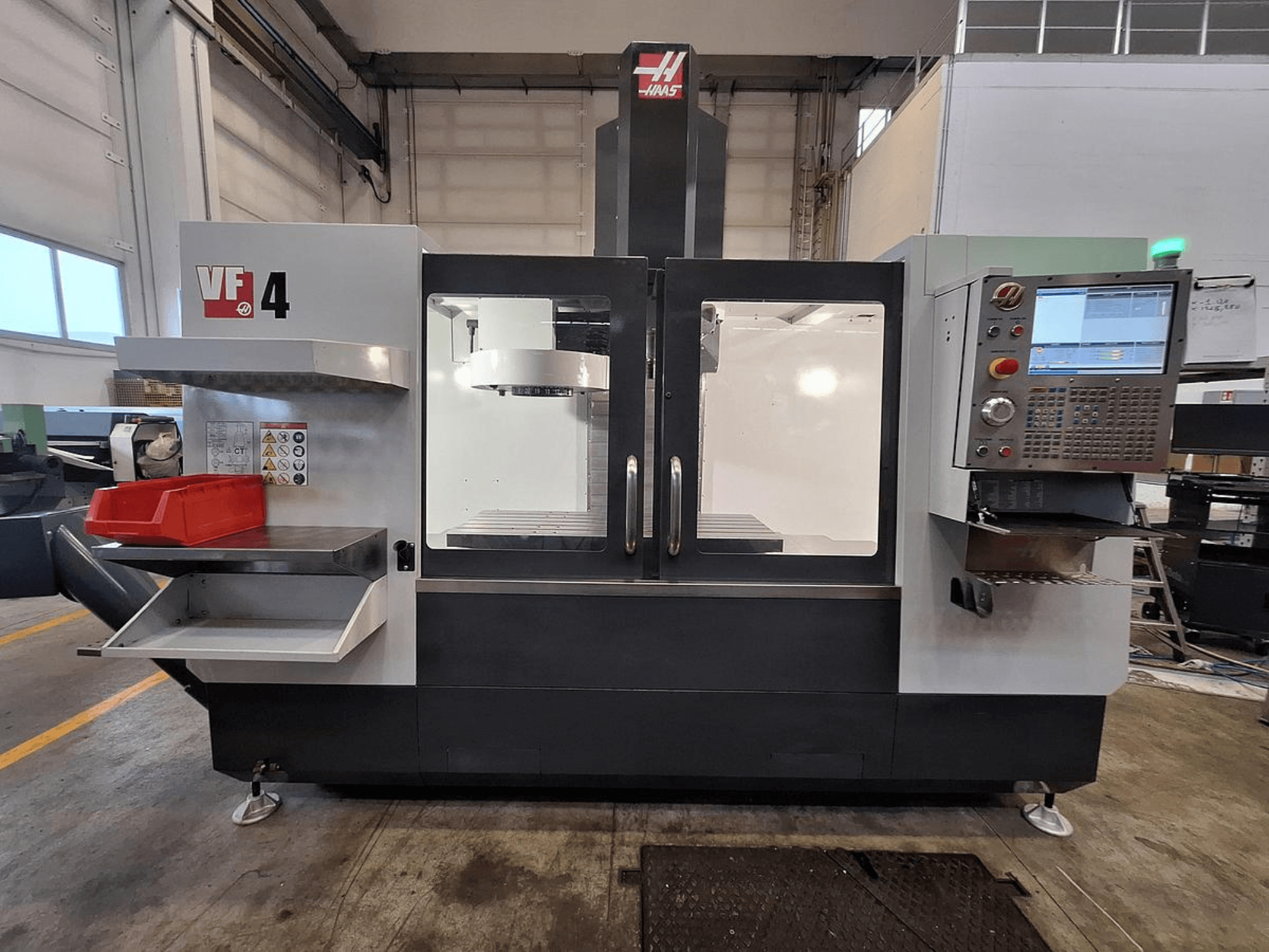 Haas VF-4 Vertikal-Bearbeitungszentrum, Vorderansicht, mit Bedienfeld, Werkzeughalter und großem Arbeitsbereich.