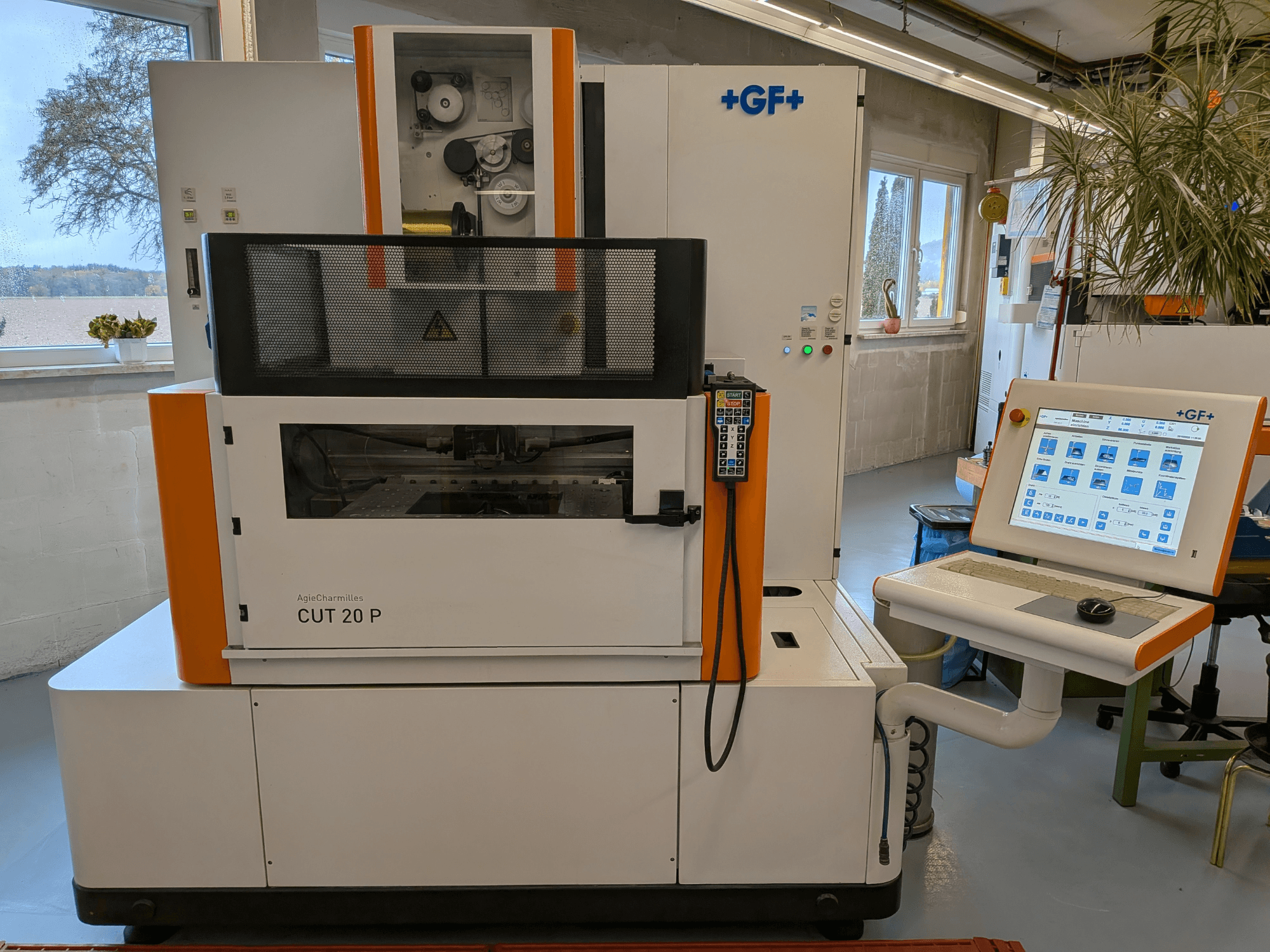 Eine AgieCharmilles Cut-20 P-Drahterodiermaschine in Frontansicht mit Bedienfeld und Display, aufgestellt in einer gut beleuchteten Werkstatt.