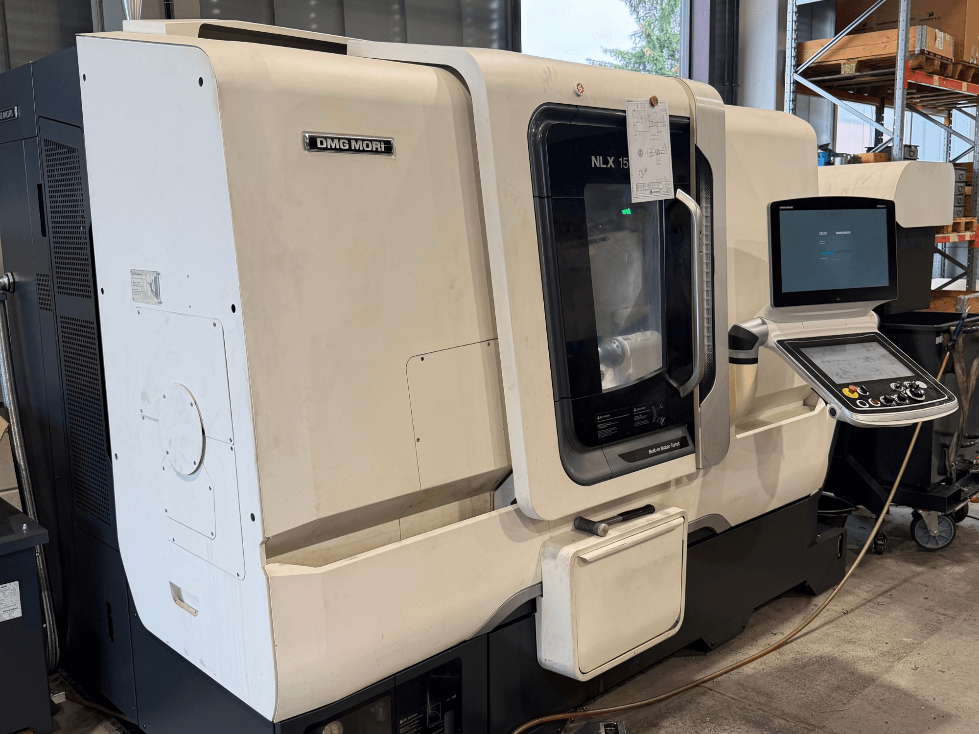 Vorderansicht der horizontalen Drehmaschine DMG MORI NLX1500MC/500, die durch die transparente Abdeckung den Blick auf das Bedienfeld und den Spindelbereich freigibt.