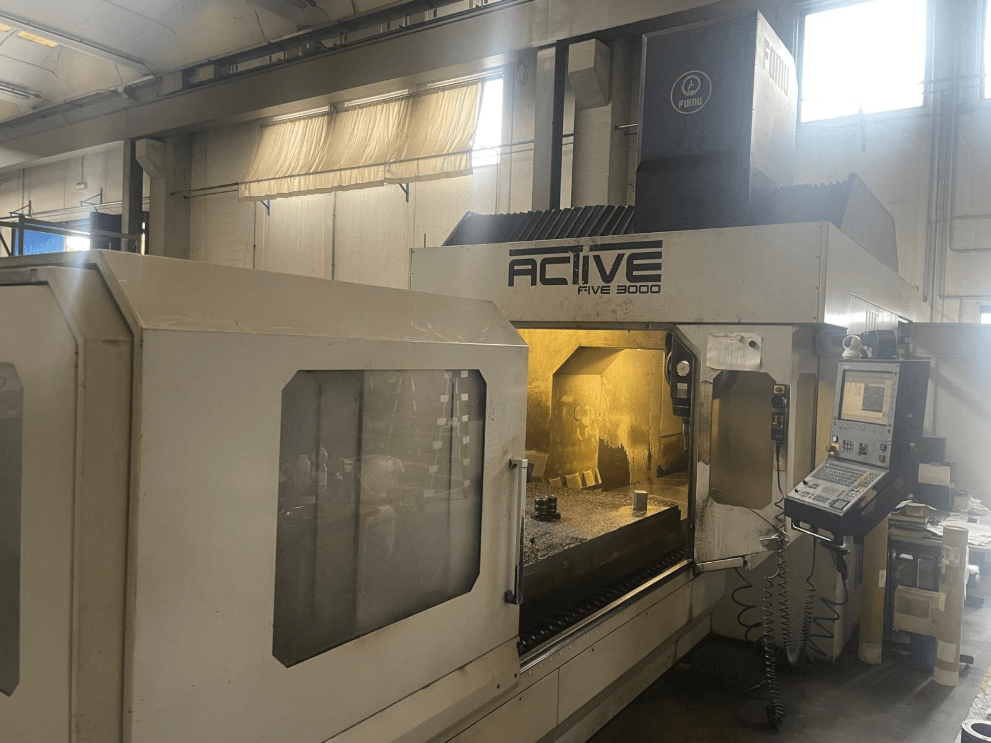 Vorderansicht der CNC-Maschine ACTIVE Five 3000 mit Bedienfeld und Arbeitsbereich mit einem teilweise bearbeiteten Teil im Inneren.