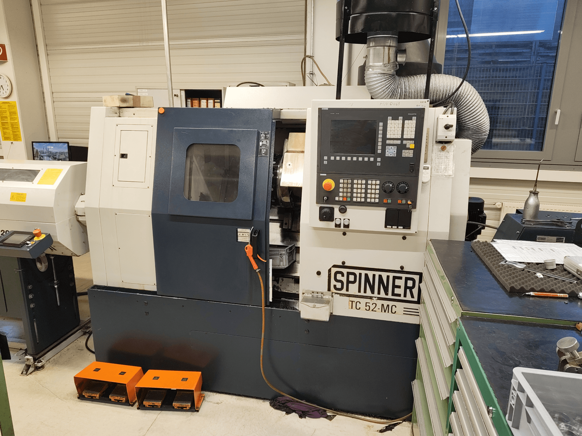 Horizontaldrehmaschine SPINNER TC 52 MC in einer Werkstatt, Vorderansicht, mit Blick auf das Bedienfeld, den Bearbeitungsbereich und die Sicherheitsvorrichtungen.