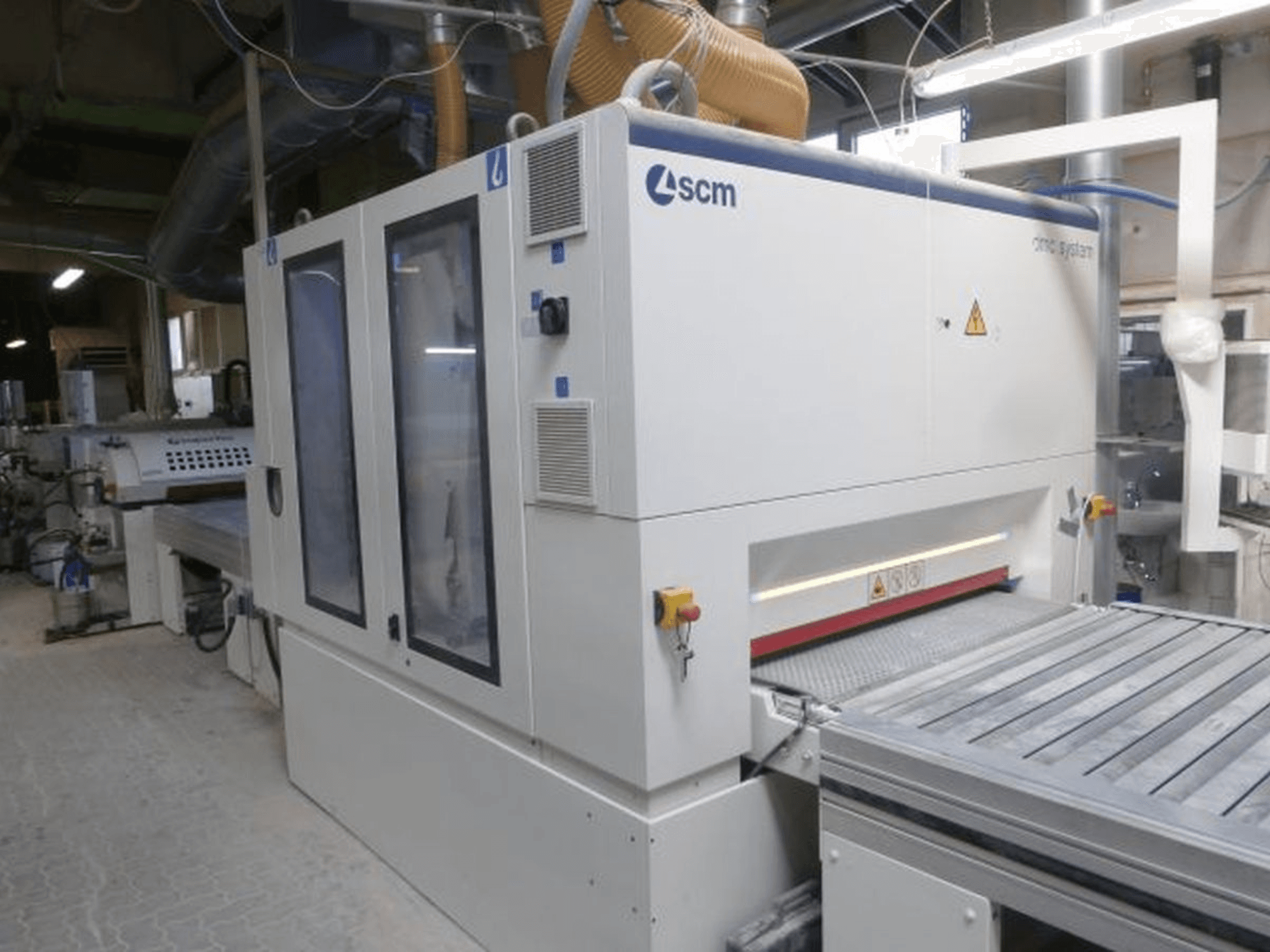 Bandschleifmaschine SCM DMC SY TC 1350 in einer Werkstatt, Seitenansicht mit Bedienfeld und Schleiffläche sowie Sicherheitsvorrichtungen.