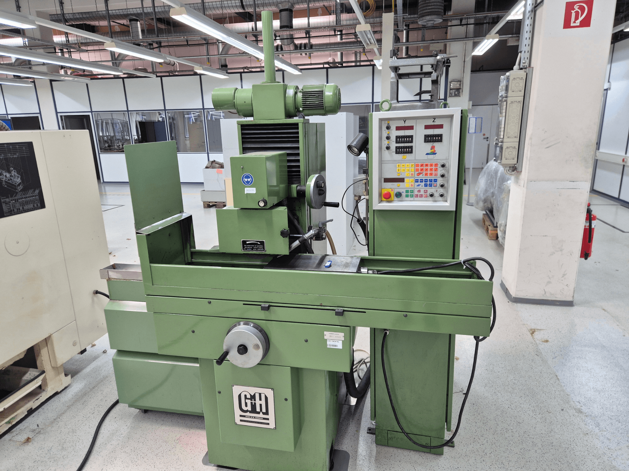 Flachschleifmaschine GEIBEL & HOTZ FS 40 SA in einer Werkstatt, mit Blick auf das Bedienfeld, den Schleiftisch und den Motor aus der Vorderansicht.