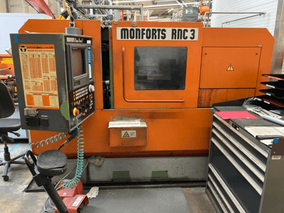 Monforts RNC 3 Maschine in Orange und Schwarz, Vorderansicht, mit Bedienfeld und verschiedenen Werkzeugschubladen.