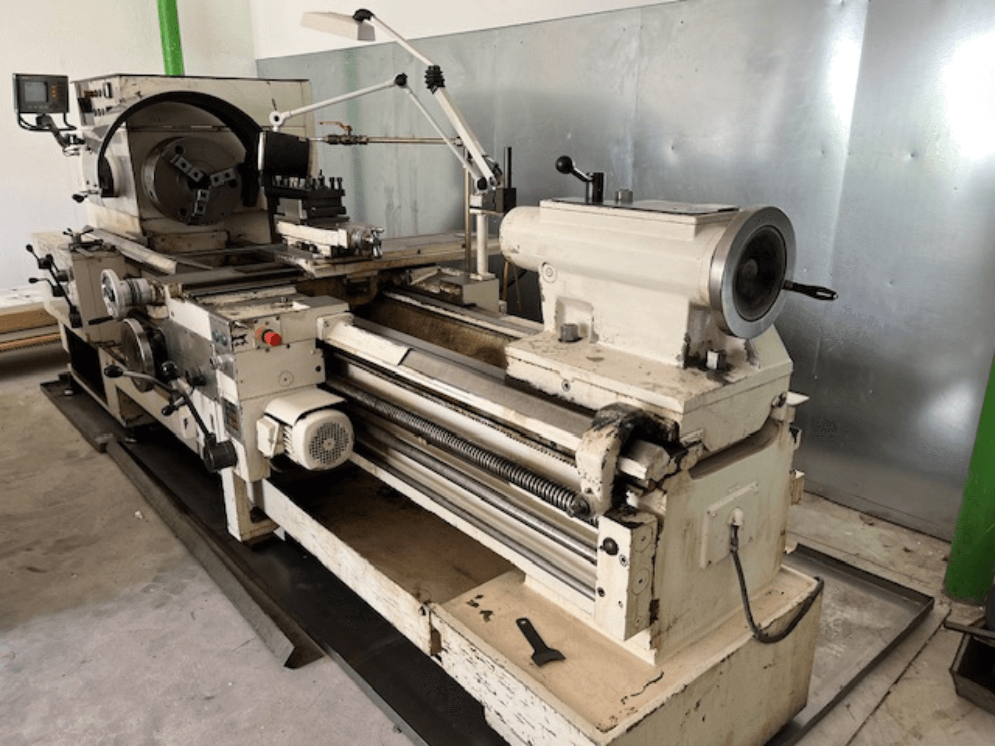 Alte Metalldrehmaschine mit Bedienfeld und Werkzeugen, Seitenansicht, mit Bedienelementen und Metalloberfläche.