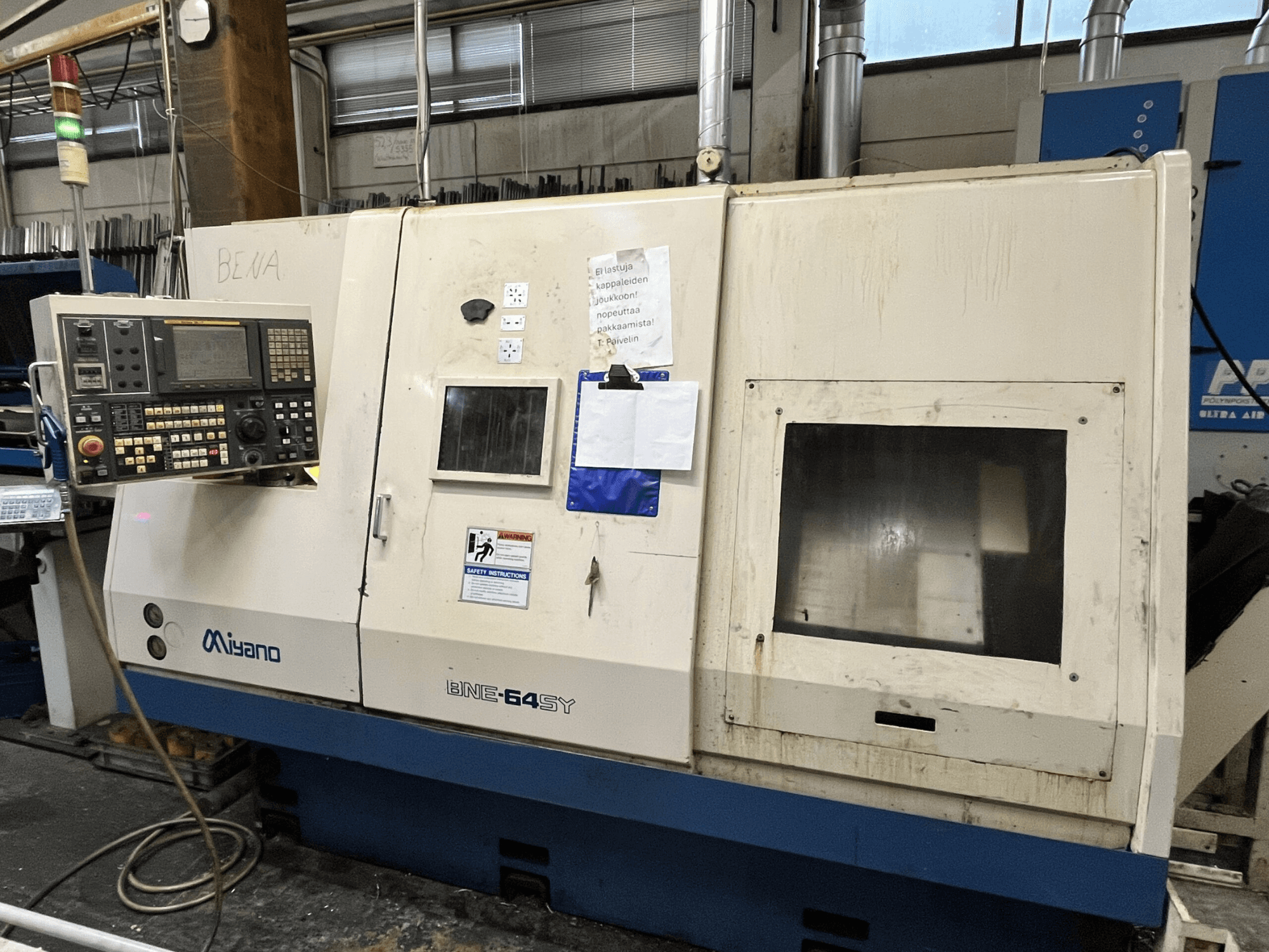 Miyano BNE-64SY CNC-Drehmaschine, Vorderansicht, mit Bedienfeld mit Tasten, LCD und Wartungsaufkleber auf dem Gehäuse.