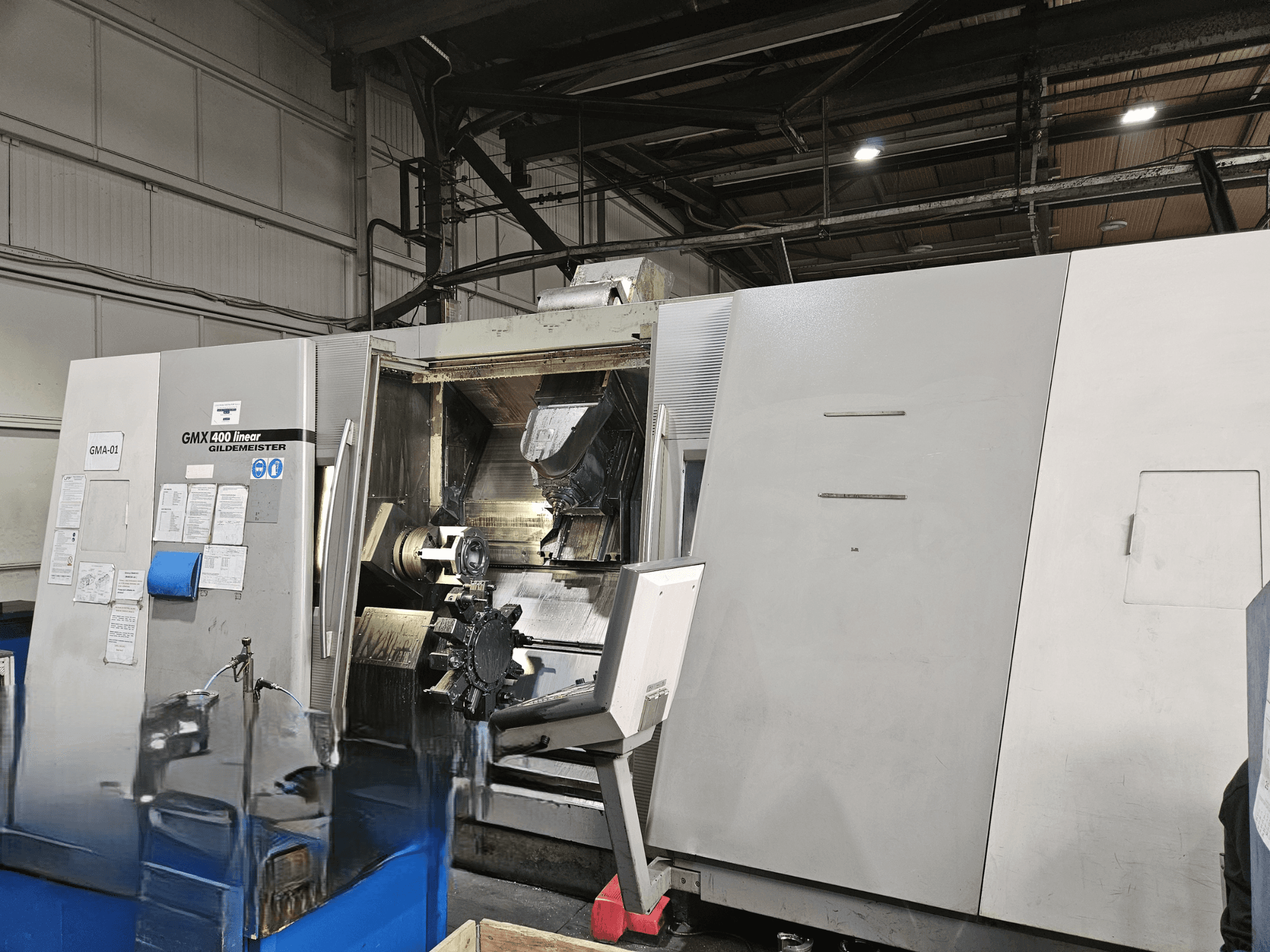 Gildemeister GMX 400 Linear-Dreh-Fräszentrum in der Vorderansicht, mit freiem Zugang zum Bearbeitungsraum und den Werkzeugen im Inneren.
