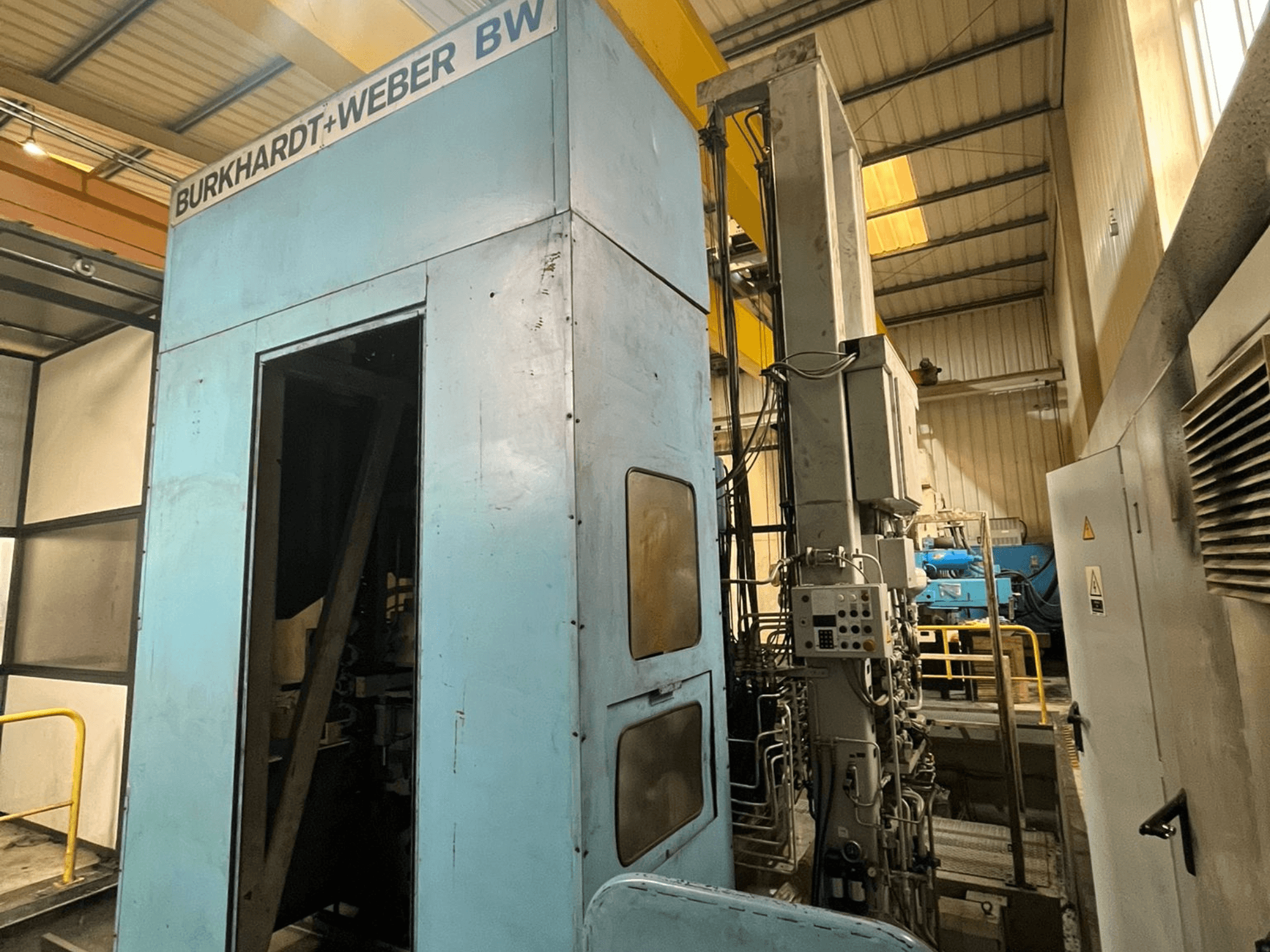 Burkhardt-Weber MC100 Horizontal-Bearbeitungszentrum, Seitenansicht mit blauer Außenverkleidung und Bedienfeld mit sichtbaren Leitungen.