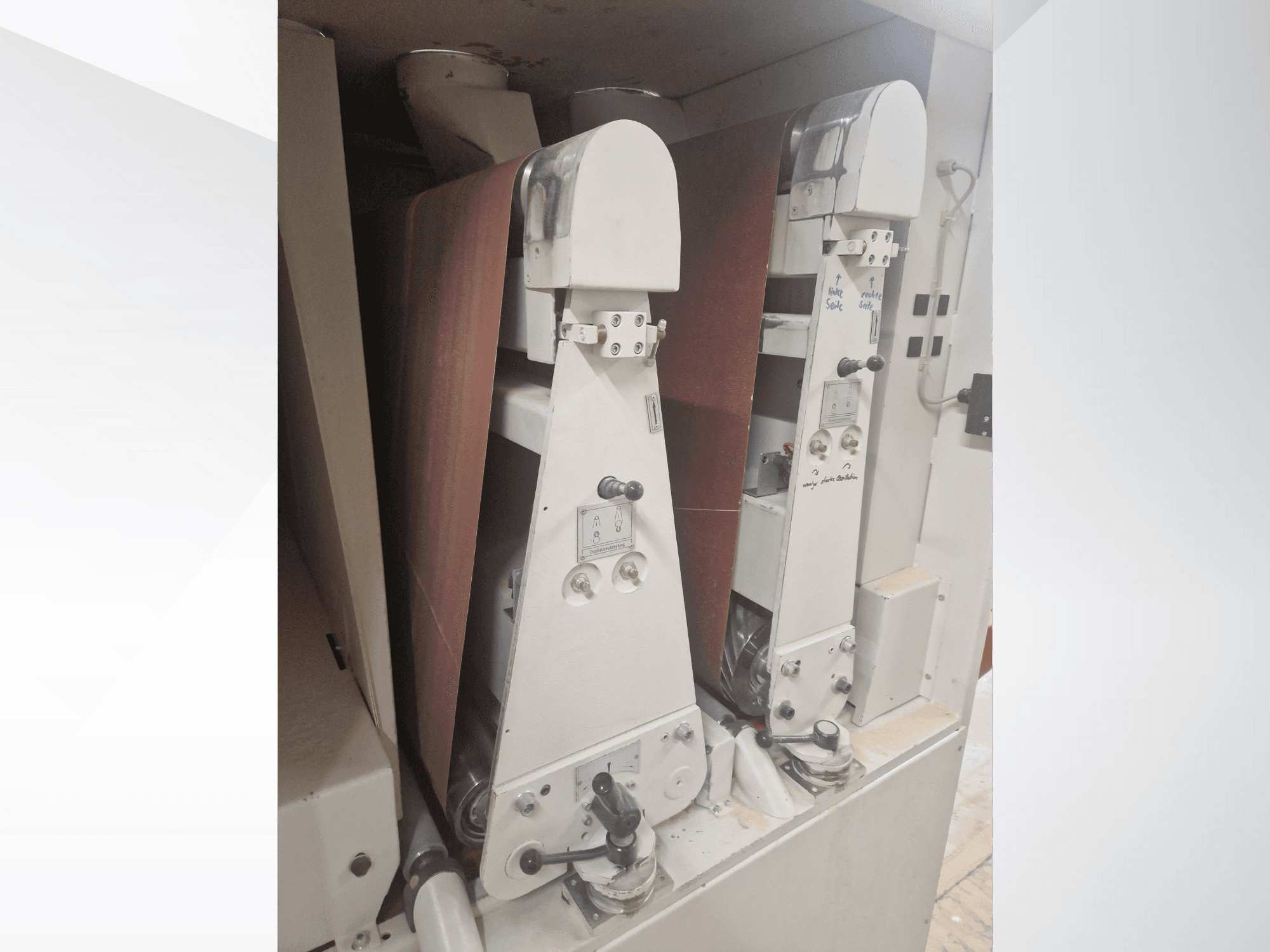 Zwei Industrie-Schleifmaschinen mit roten Schleifbändern, Vorderansicht, mit Bedienelementen und Metallteilen.