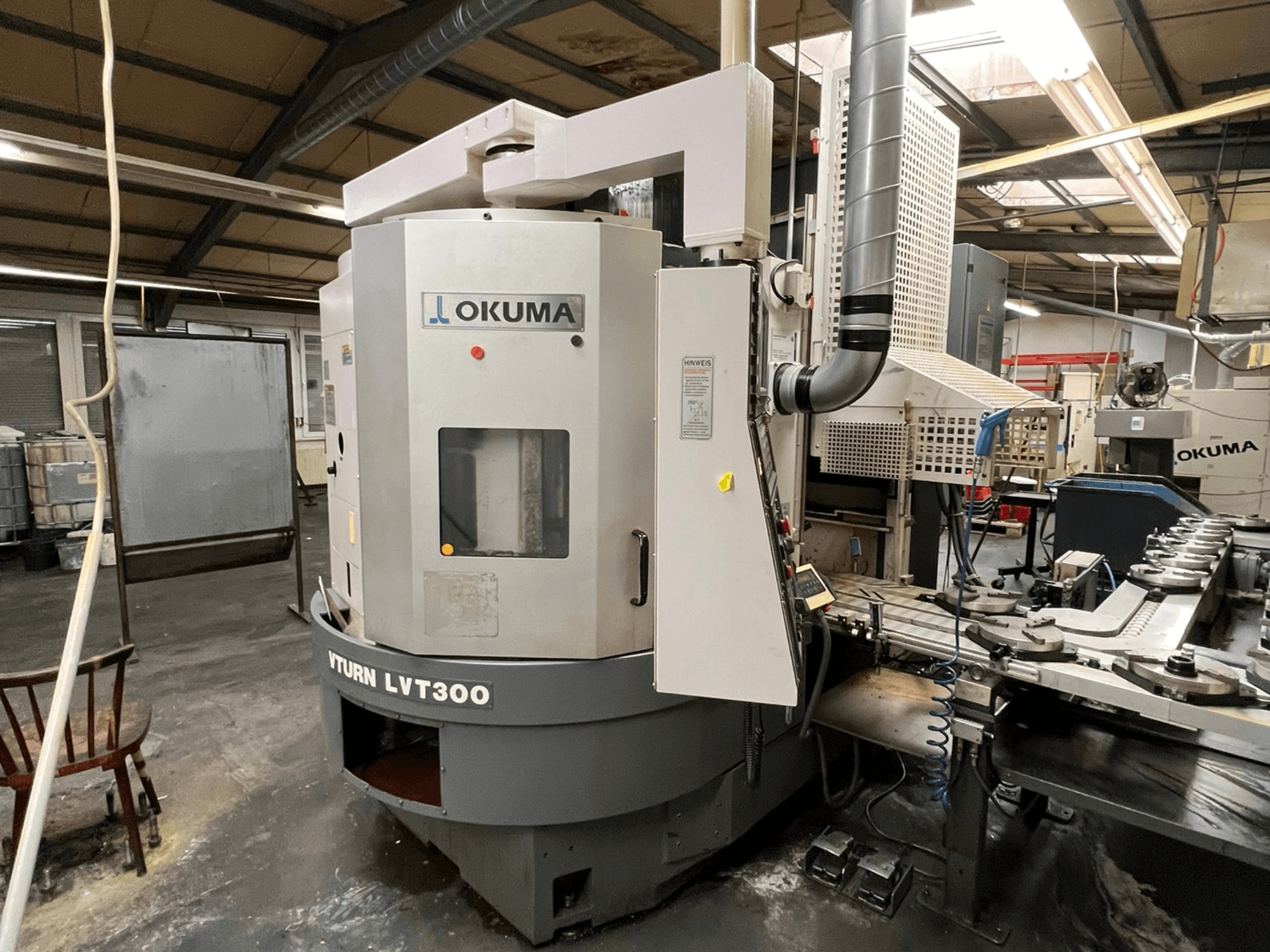 Okuma Vturn LVT300 CNC-Drehmaschine, Seitenansicht in Industrieumgebung, mit Bedienfeld und Kühlmittelsystem.