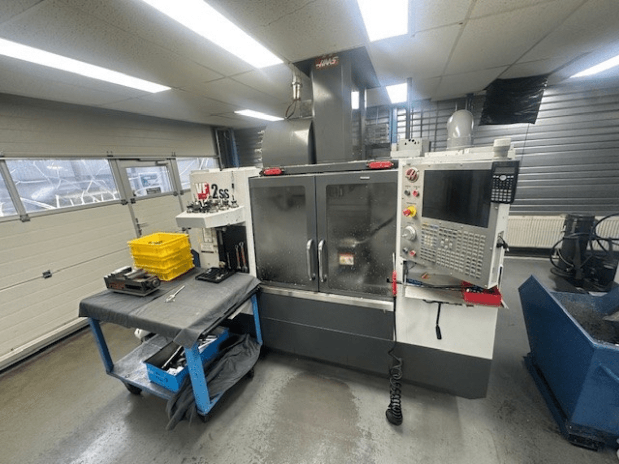 Frontansicht des HAAS VF-2SS Vertikal-Bearbeitungszentrums mit Bedienpult, Arbeitstisch und Werkzeugspeicherstation.