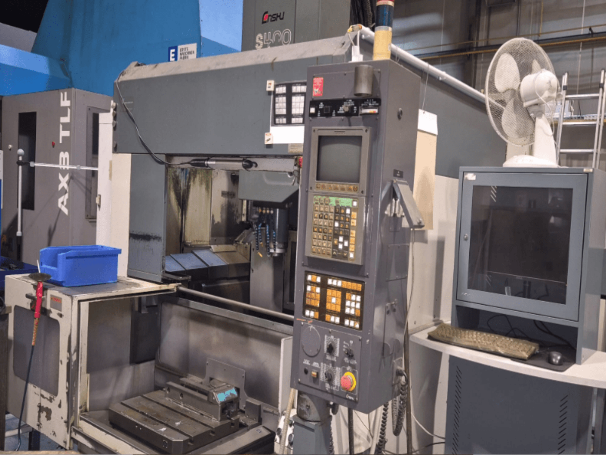 Vertikales Bearbeitungszentrum Enshu S400 in einer Werkstatt, mit Bedienfeld, Monitor und Arbeitsbereich der Maschine.