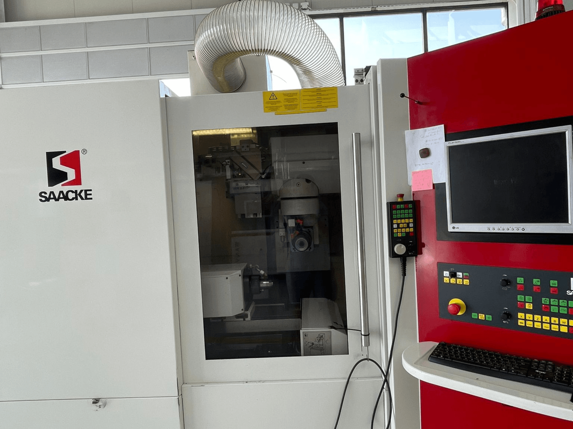 SAACKE-Maschine in Weiß und Rot, Vorderansicht, mit Bedienfeld, Monitor und durch Glas sichtbaren Innenteilen.