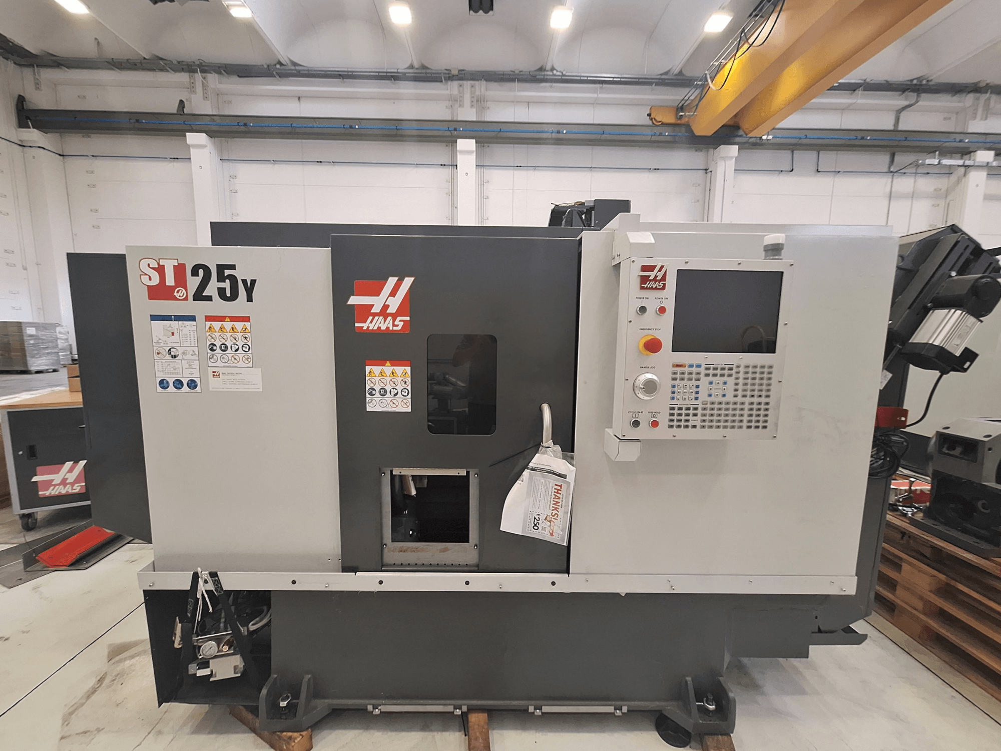 Horizontaldrehmaschine Haas ST-25Y, Vorderansicht, mit Bedienfeld und Sicherheitshinweisen. Ideal für die Präzisionsbearbeitung.