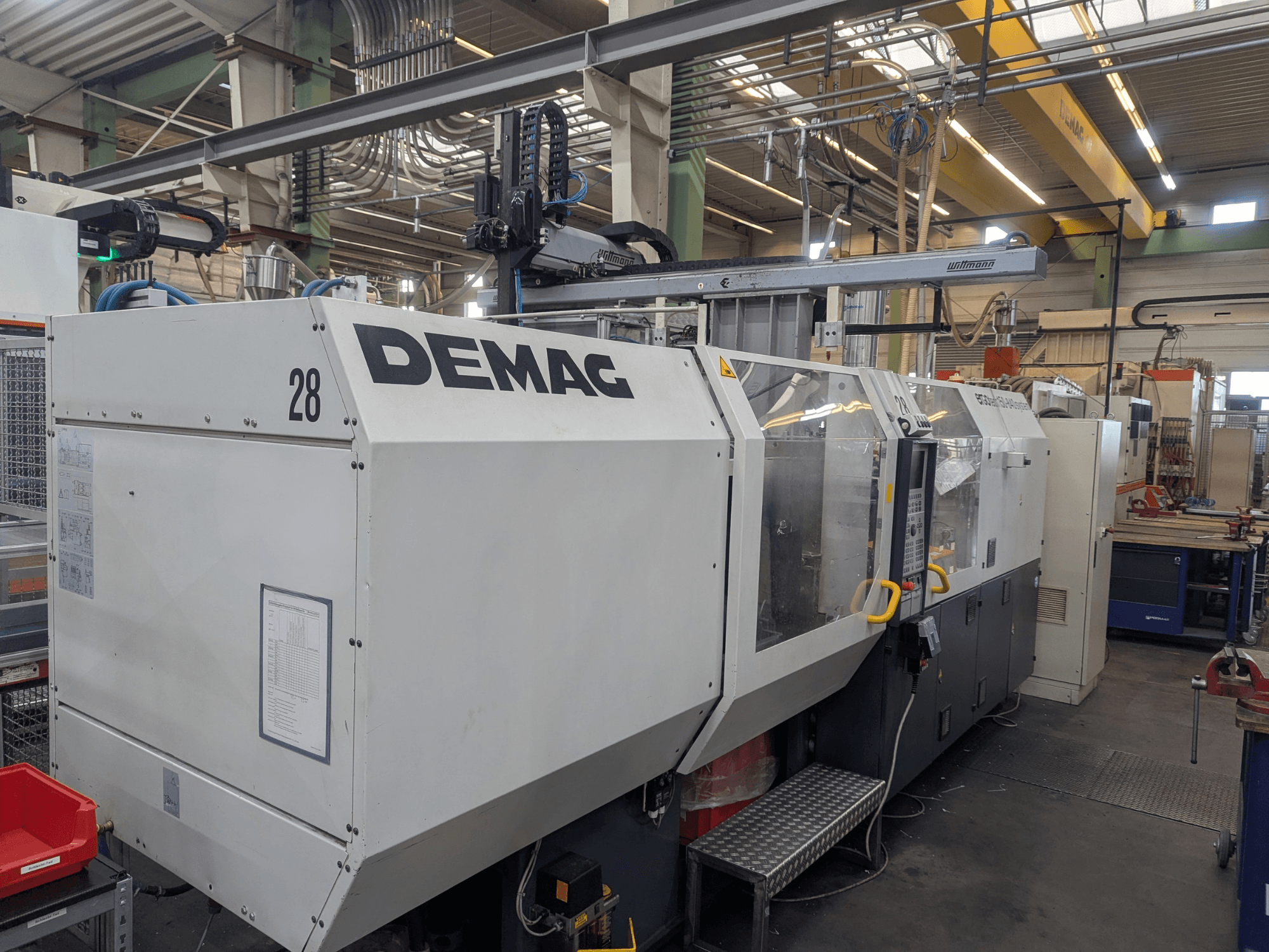 Frontansicht einer hydraulischen Spritzgießmaschine DEMAG ERGOTECH 1500-840, die die Bedienelemente und Sicherheitseinrichtungen zeigt.