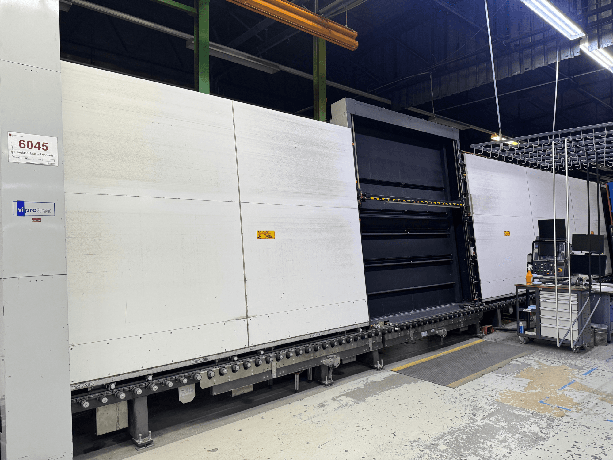 Vorderansicht der Vipro-Formmaschine mit offener Platte, die die Betriebsausrüstung und den daneben liegenden Arbeitsbereich zeigt. Modell 6045.