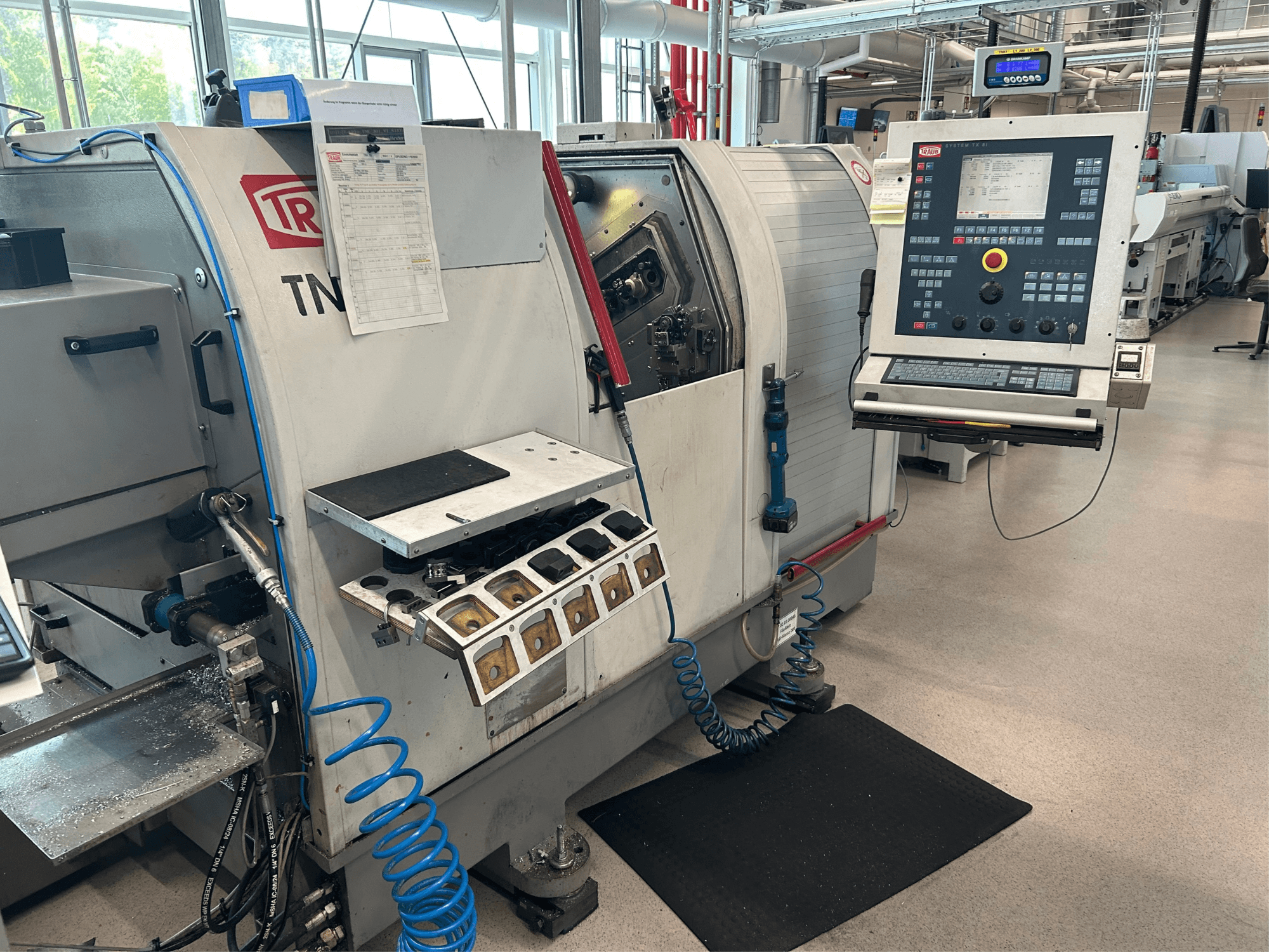 Horizontal-Drehmaschine TRAUB TNK 36, Vorderansicht, mit Bedienpult, Werkzeughalter und Arbeitsbereich mit Spänen.