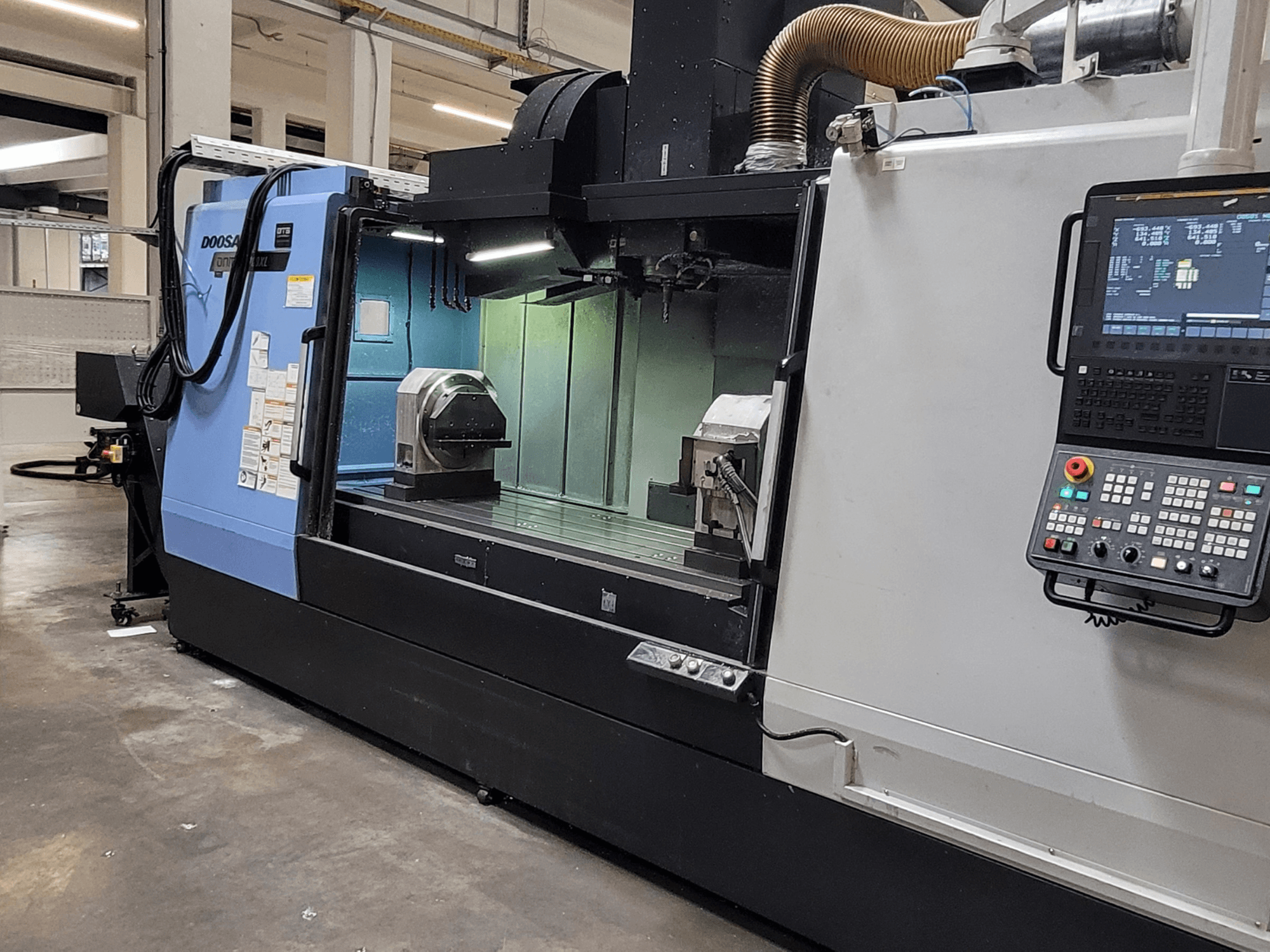 Vertikales Bearbeitungszentrum DOOSAN DNM 6700 XL, Vorderansicht mit Bedienfeld, Arbeitstisch und Bearbeitungsbereich.