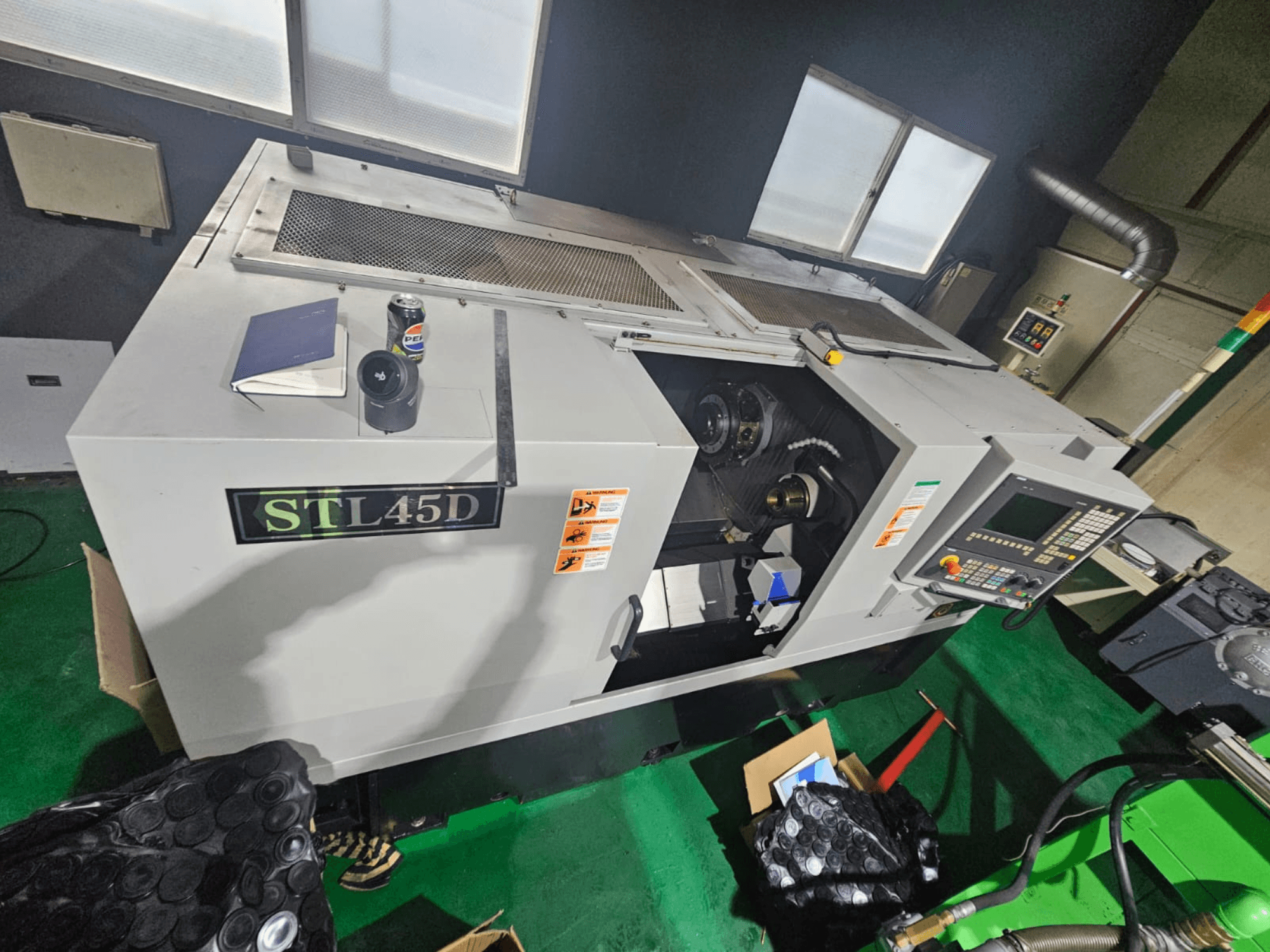 STL45D CNC-Maschine von oben gesehen, mit Bedienfeld, zylindrischem Teil, Notebook und Dose oben.