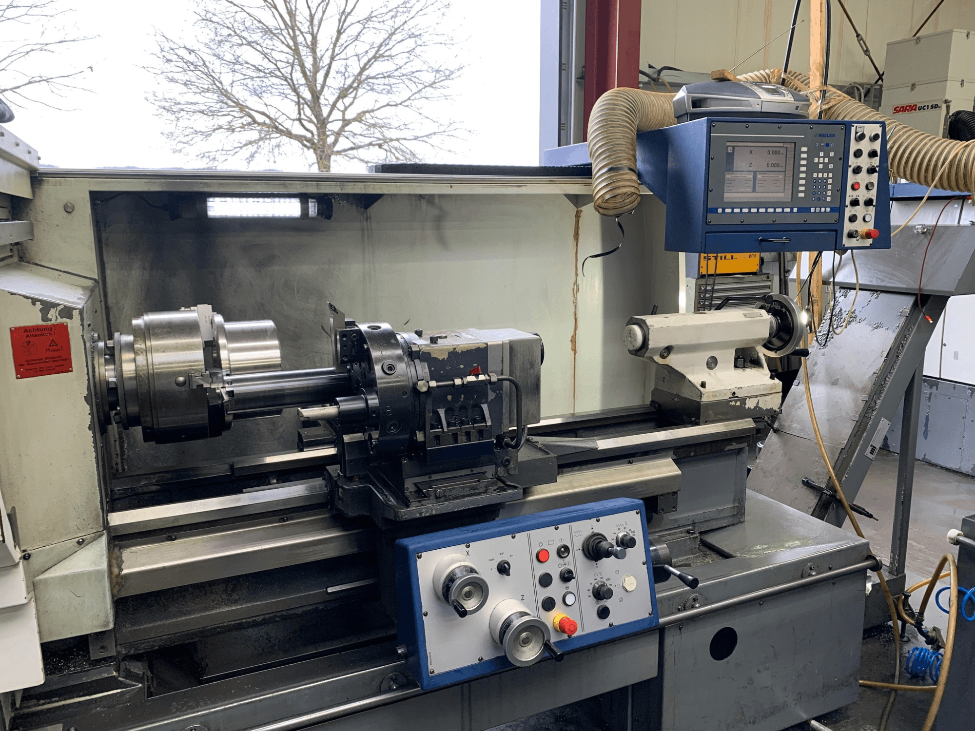 Weiler E55X1000 Horizontal-Drehmaschine in einer Werkstatt, mit Bedienfeld, Drehbank und Werkzeughalter. Ansicht von vorne.