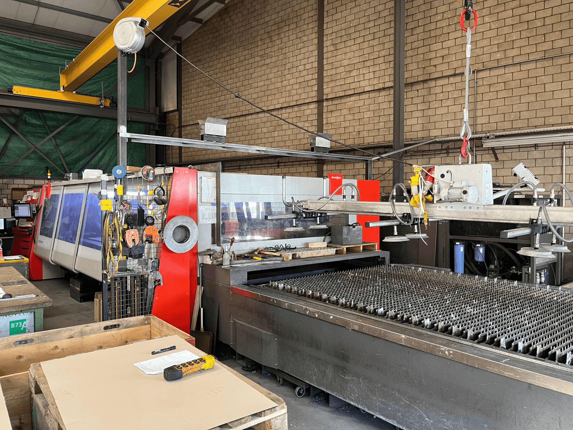 CO₂-Laserschneidmaschine Bystronic ByAutonom 4020, Seitenansicht mit Arbeitstisch, Bedienfeld und Laufkran im Hintergrund.